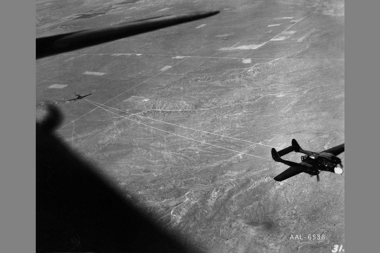 NACA photographer Northrop P-61A Black Widow towing P-51B to release altitude of 28,000 ft over Muroc Dry Lake, California for in flight validating of wind tunnel measurements of drag. After the pilot released the tow cable, drag measurementrs were obtained at various airspeeds in a 20-minute unpowered flight.  Note:  Used in publication in Flight Research at Ames;  57 Years of Development and Validation of Aeronautical Technology  NASA SP-1998-3300  Fig. 17