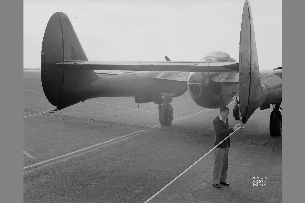 Towing installations on P-51 and P-61 airplanes for propeller off tests on the P-51. Rear view of P-61 in towing position preparing for take off at NACA Ames Research Center, Moffett Field, California