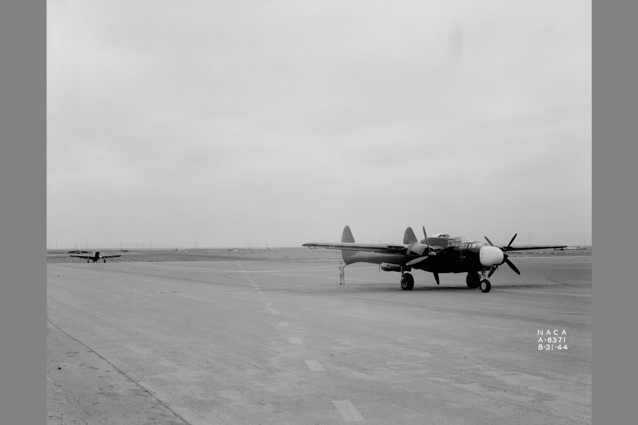 Towing installations on P-51 and P-61 airplanes for propeller off tests on the P-51 Front view of P-51 & P-61 in towing position preparing for take off at NACA Ames Research Center, Moffett Field, California