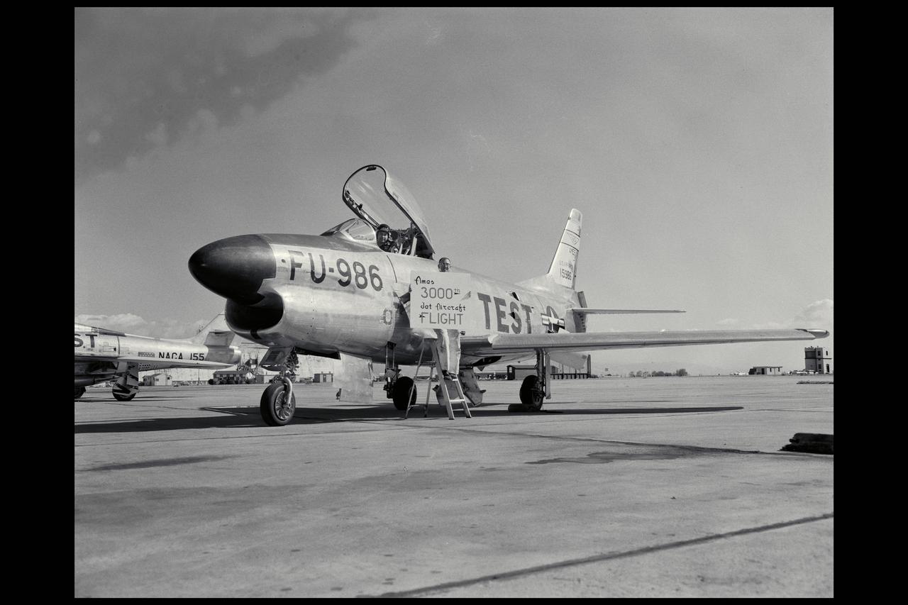 NACA/Ames photographer North American F-86D with Pilot Robert C Innis and Crew Chief Russell O. Barton hold sign celebrating Ames 3000th jet aircraft flight