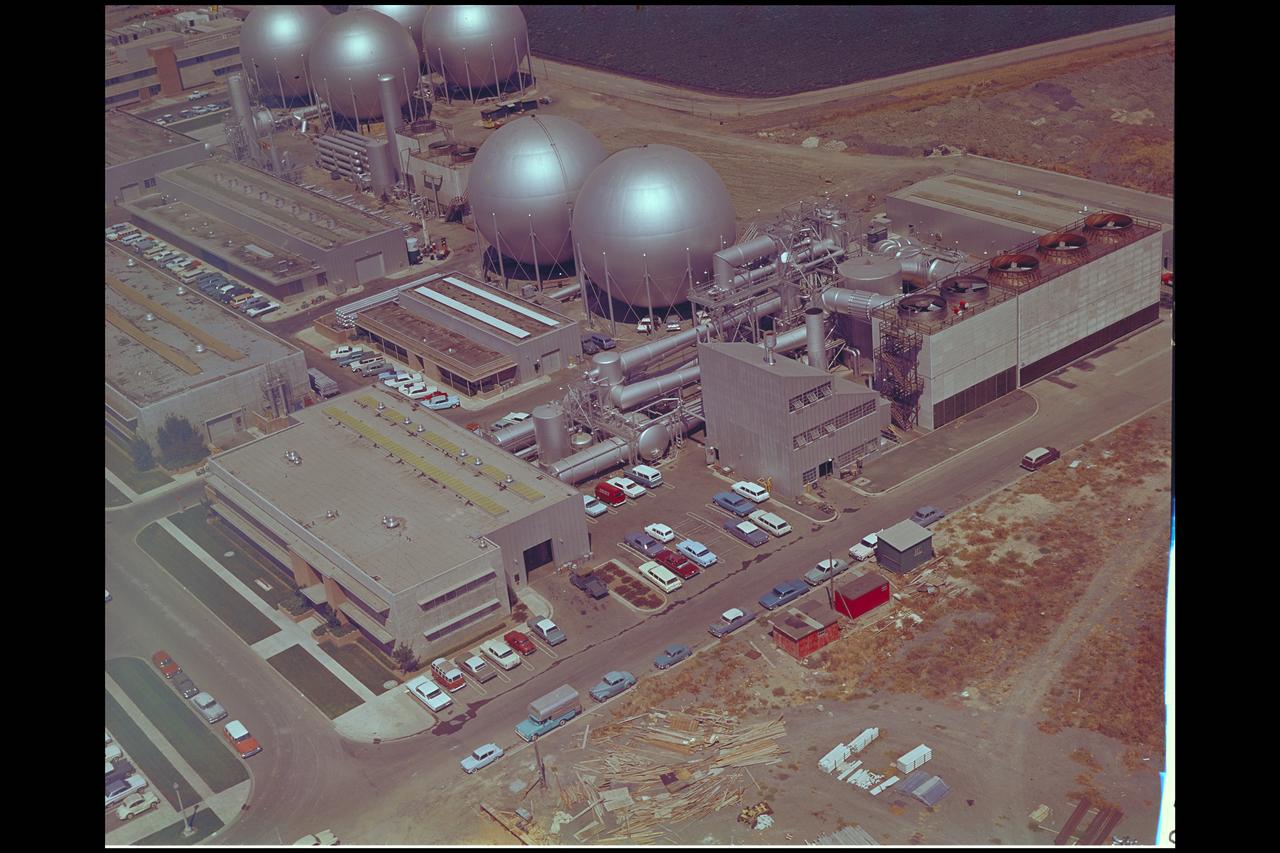Aerial view of Gasdynamics facility in 1964 and the 20 inch helium tunnel Part of the Thermal Protection Laboratory used to research materials for heat shield applications and for aerodynamic heating and materials studies of vehicles in planetary atmospheres.  This laboratory is comprised of five separate facilities: an Aerodynamic Heating Tunnel,  a Heat Transfer Tunnel, two Supersonic Turbulent Ducts, and a High-Power CO2 Gasdynamic Laser. All these facilities are driven by arc-heaters, with the exception of the large, combustion-type laser.  The arc-heated facilities are powered by a 20 Megawatt DC power supply. Their effluent gas stream (test gases; Air, N2, He, CO2 and mixtures; flow rates from 0.05 to 5.0 lbs/sec) discharges into a five-stage stream-ejector-driven vacuum system. The vacuum system and power supply are common to the test faciities in building N-238. All of the facilities have high pressure water available at flow rates up to 4, 000 gals/min. The data obtained from these facilities are recorded on magnetic tape or oscillographs. All forms of data can be handled whether from thermo-couples, pressure cells, pyrometers, or radiometers, etc. in addition, closed circuit T. V. monitors and various film cameras are available. (operational since 1962)
