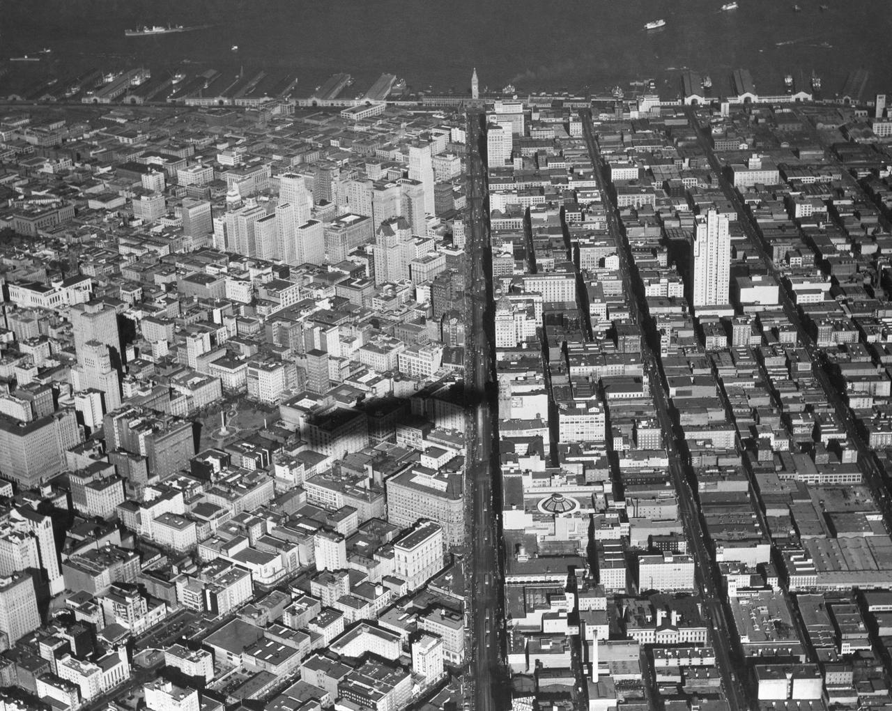 Navy Aerial of San Francisco, California; over downtown lookin down Market Street toward Ferry Building (shadow of U.S. Macon)