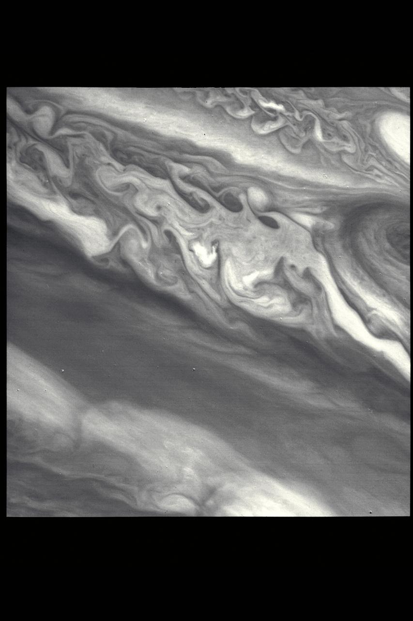 P-21735 BW This Jupiter image taken by Voyager 2 shows an area from 10° N. Lat. to 34° S. Lat. in a region west of the Great Red Spot. At the top of the picture, equatorial plumes are seen. These features move along the edge of the equatorial zone. The remainder of the equatorial region is characterized by diffuse clouds. The region west of the Great Red Spot is seen as a disturbed wave-like pattern. Similiar flows are seen to the west of the white oval at bottom.
