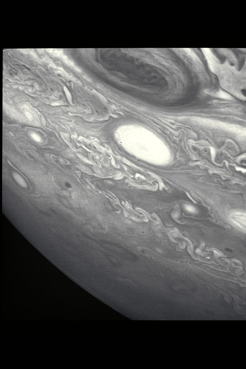 P-21737 BW This picture shows a region of the southern hemisphere extending from the Great Red Spot to the south pole. The white oval is seen beneath the Great Red Spot, and several small scale spots are visible farther to the south. Some of these organized cloud spots have similiar morphologies, such as anticyclonic rotations and cyclonic regions to their west. The presence of the white oval causes the streamlines of the flow to bunch up between it and the Great Red Spot.