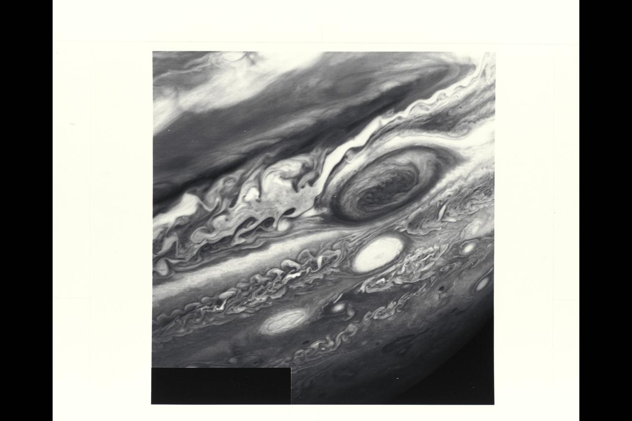 P-21742 BW Range: 6 million kilometers (3.72 million miles) This Voyager 2 image shows the region of Jupiter extending from the equator to the southern polar latitudes in the neighborhood of the Great Red Spot. A white oval, different from the one observed in a similiar position at the time of the Voyager 1 encounter, is situated south of the Great Red Spot. The region of white clouds now extends from east of the red spot and around its northern boundary, preventing small cloud vortices from circling the feature. The disturbed region west of the red spot has also changed since the equivalent Voyager 1 image. It shows more small scale structure and cloud vortices being formed out of the wave structures.