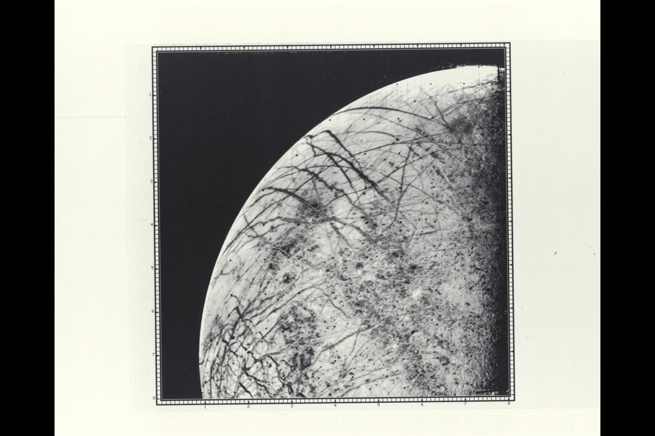 P-21758 BW Range: 246,000 kilometers (152,000 miles) This picture by Voyager 2 is the first close look ever obtained of Jupiter's satellite, Europa. The linear crack-like features had been seen from a much greater distance by Voyager 1 but this image provides a resolution of about four kilometers (2.5 miles). The complicated linear features appear even more like cracks or huge fractures in these images. Also seen are somewhat darker mottled regions which appear to have a slightly pitted appearance, perhaps due to small scale craters. No large craters (more than five kilometers in diameter) are easily identifiable in the Europa photographs to date, suggesting that this satellite has a young surface relative to Ganymede and Callisto, although not perhaps as young as Io's. Various models for Europa's structure will be tested during analysis of these images, including the possibility that the surface is a thin ice crust overlying water or softer ice and that the fracture systems seen are breaks in that crust. Resurfacing mechanisms such as production of fresh ice or snow along the cracks and cold glacier-like flows are being considered as possibilities for removing evidence of impact events. Europa thus appears to truly be a satellite with many properties intermediate between Ganymede and Io.