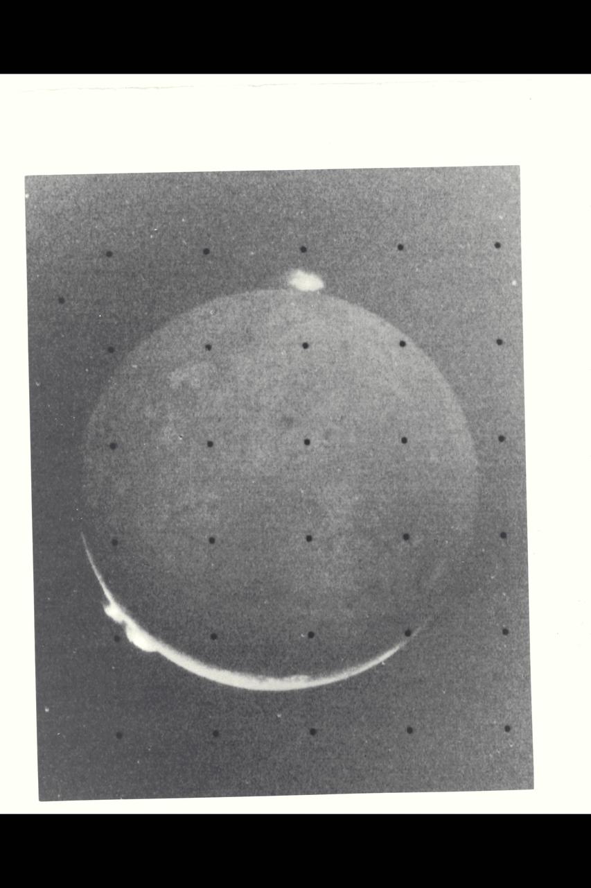 Range :  1.2 million kilometers (750,000 miles) This picture of Io is one of the last sequence of 'volcano watch' pictures planned as a time lapse study of the nearest of Jupiter's Galilean satellites.  The sunlit crescent of Io is seen at the left, and the night side illuminated by light reflected from Jupiter can also be seen.  Three volcanic eruption plumes are visible on the limb.  All three were previously seen by Voyager 1.  On the bright limb Plume 5 (upper) and Plume 6 (lower) are about 100 km high, while Plume 2 on the dark limb is about 185 km high and 325 km wide.  The dimensions of Plume 2 are about 1 1/2 times greater than during the Boyager 1 encounter, indicating that the intensity of the eruptions has increased during the four-month time interval between the Boyager encounters.  The three volcanic eruptions and at least three others have apparently been active at roughly the same intesity or greater for a period of at least four months.