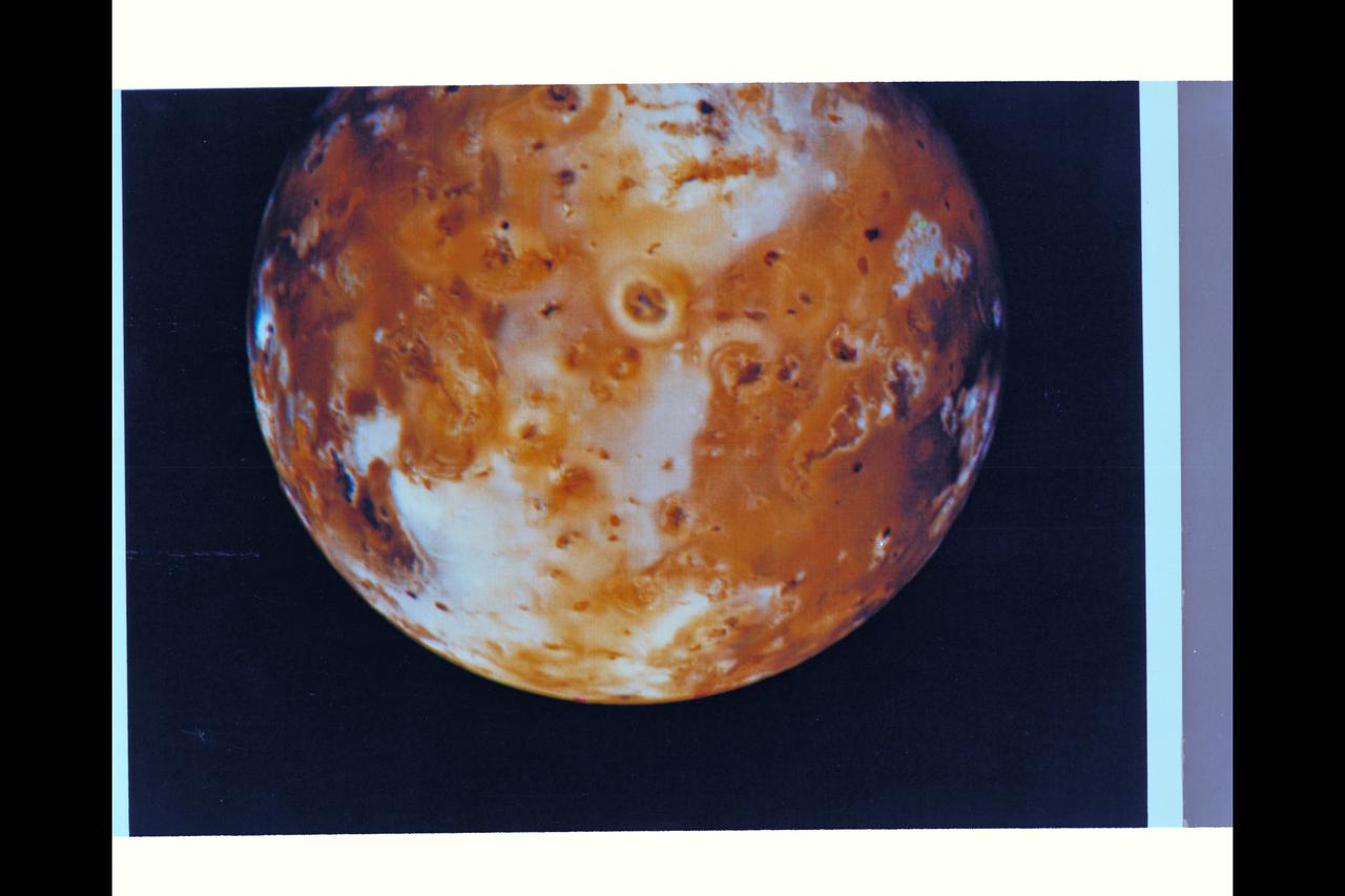 Range :  862,200 km. ( 500,000 miles ) This photograph shows subspacecraft longitude of approximately 146 degrees of Jupiter's moon Io. Circular features are seen that may be meteorite impact craters or features of internal origins.  Irregular depressions are seen that indicate surface modifications. The bright irregular patches appear to be younger deposits masking the surface detail.