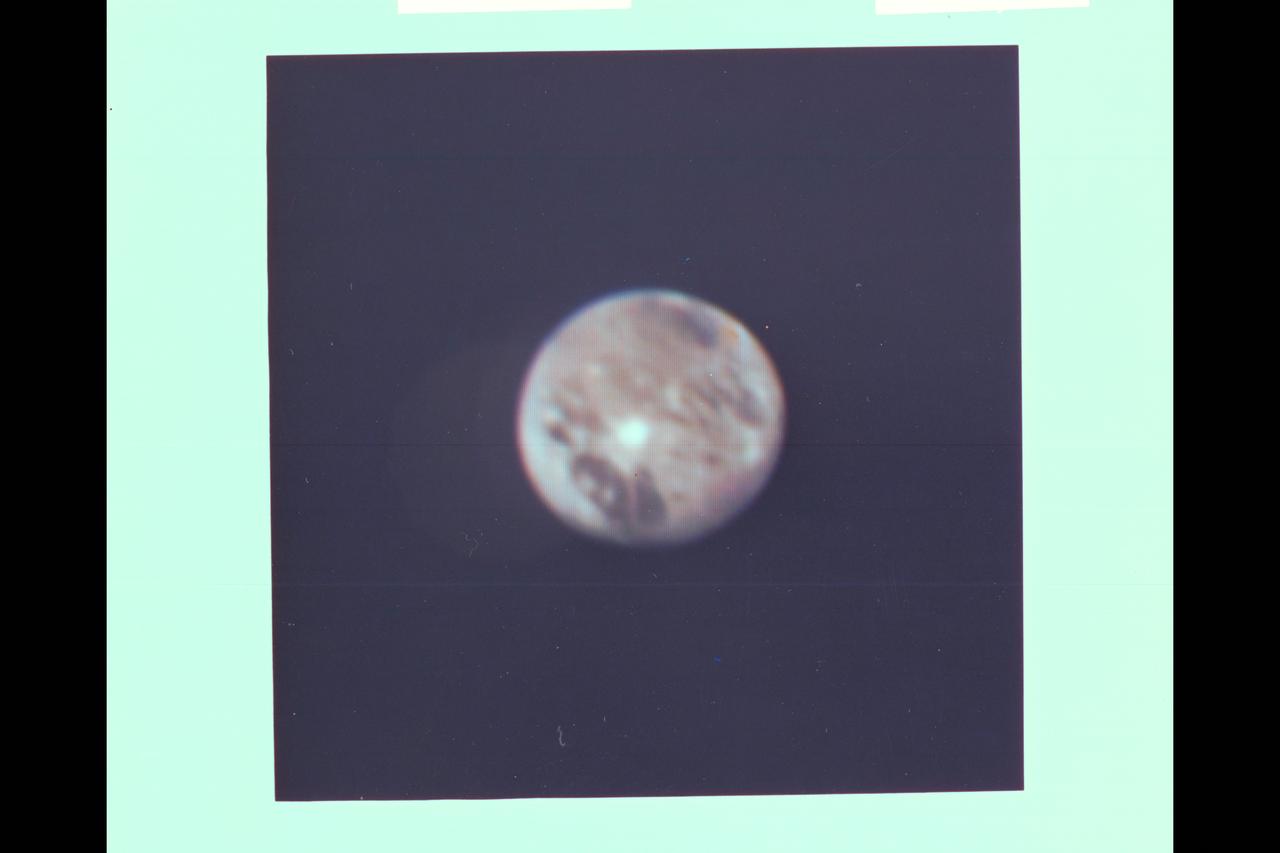 Range :  5 million miles (8.025 million kilometers) This is a morning shot of Ganymede, largest of Jupiter's 13 satellites.  It's slightly larger than Mercury with a density  about twice that of water.  It's believed to be made of rock and ice with a surface of water and ice.  Ganymede is 4 times brighter than our Moon with the bright spot in center of photo 5 times brighter than the Moon, and may contain more ice than surrounding areas.  The bright pattern around the spot seems like ray craters on the Moon and Mercury and the area may in fact be an impact crater that has exposed fresh, underlying ice.  Photo taken through blue, green and orange filters.