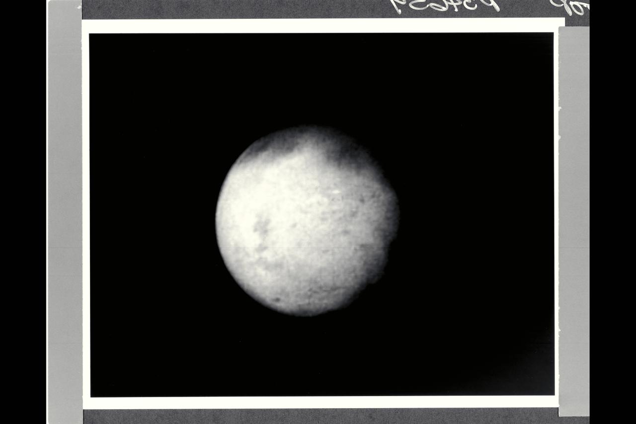 Range :  660,000 kilometers (400,000 miles) Time :  5:05 am PST This Voyager 1 picture of Mimas shows a large impact structure at 110 degrees W Long., located on that face of the moon which leads Mimas in its orbit.  The feature, about 130 kilometers in diameter (80 miles), is more than 1/4 the diameter of the entire moon.  This is a particularly interesting feature in view of its large diameter compared with the size of the satellite, and may have the largest crater diameter/satillite diameter ratio in the solar system.  The crater has a raised rim and central peak, typical of large impact structures on terrestrial planets.  Additional smaller craters, 15-45 kilometers in diameter, can be seen scattered across the surface, particularly alon the terminator.  Mimas is one of the smaller Saturnian satellites with a low density implying its chief component is ice.