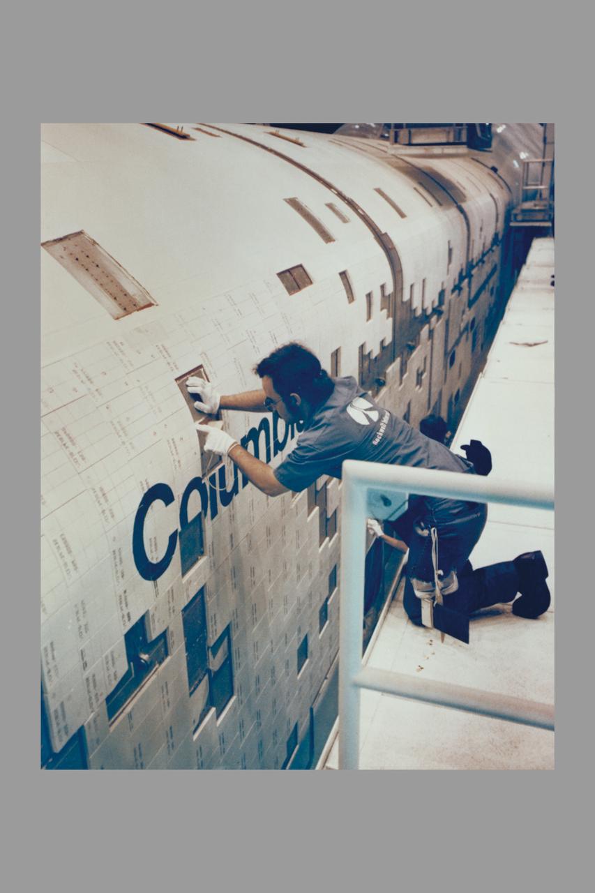 ROCKWELL INTERNATIONAL TECHNICIANS MOUNT SOME OF THE NEARLY 8,000 CERAMIC-COATED TILES THAT REMAIN TO BE INSTALLED ON THE EXTERNAL SURFACES OF THE SPACE SHUTTLE ORBITER COLUMBIA TO COMPLETE THE THERMAL PROTECTION SYSTEM THAT WILL ABSORB THE INTENSE HEAT OF REENTERING THE EARTH'S ATMOSPHERE AFTER A MISSION IN SPACE. TILE INSTALLATION IS DONE ON AN AROUND-THE-CLOCK BASIS IN THE ORBITER PROCESSING FACILITY WHERE COLUMBIA, THE FIRST IN A NEW BREED OF MANNED, REUSABLE SPACECRAFT, IS BEING READIED FOR THE FIRST LAUNCH OF THE SPACE SHUTTLE LATER THIS YEAR.