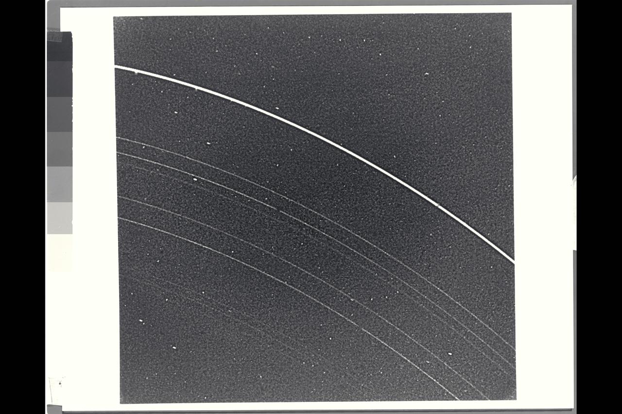 Range : 2.52 million miles (1.56 million miles) P-29481B/W Voyager 2 returned this photograph with all nine known Uranus rings visible from a 15 sec. exposure through the narrow angle camera. The rings are quite dark and very narrow. The most prominent and outermost of the nine, Epsilon, is seen at top. The next three in toward Uranus, called Delta, Gamma, and Eta, are much fainter and more narrow than Epsilon ring. Then come Beta and Alpha rings, and finally, the innermost grouping, known simply as the 4,5, & 6 rings. The last three are very faint and are at the limit of detection for the Voyager camera. Uranus' rings range in width from about 100 km. (60 mi.) at the widest part of the Epsilon ring, to only a few kilometers for most of the others. this iamge was processed to enhance narrow features; the bright dots are imperfections on the camera detector. The resolution scale is about 50 km. (30 mi.)