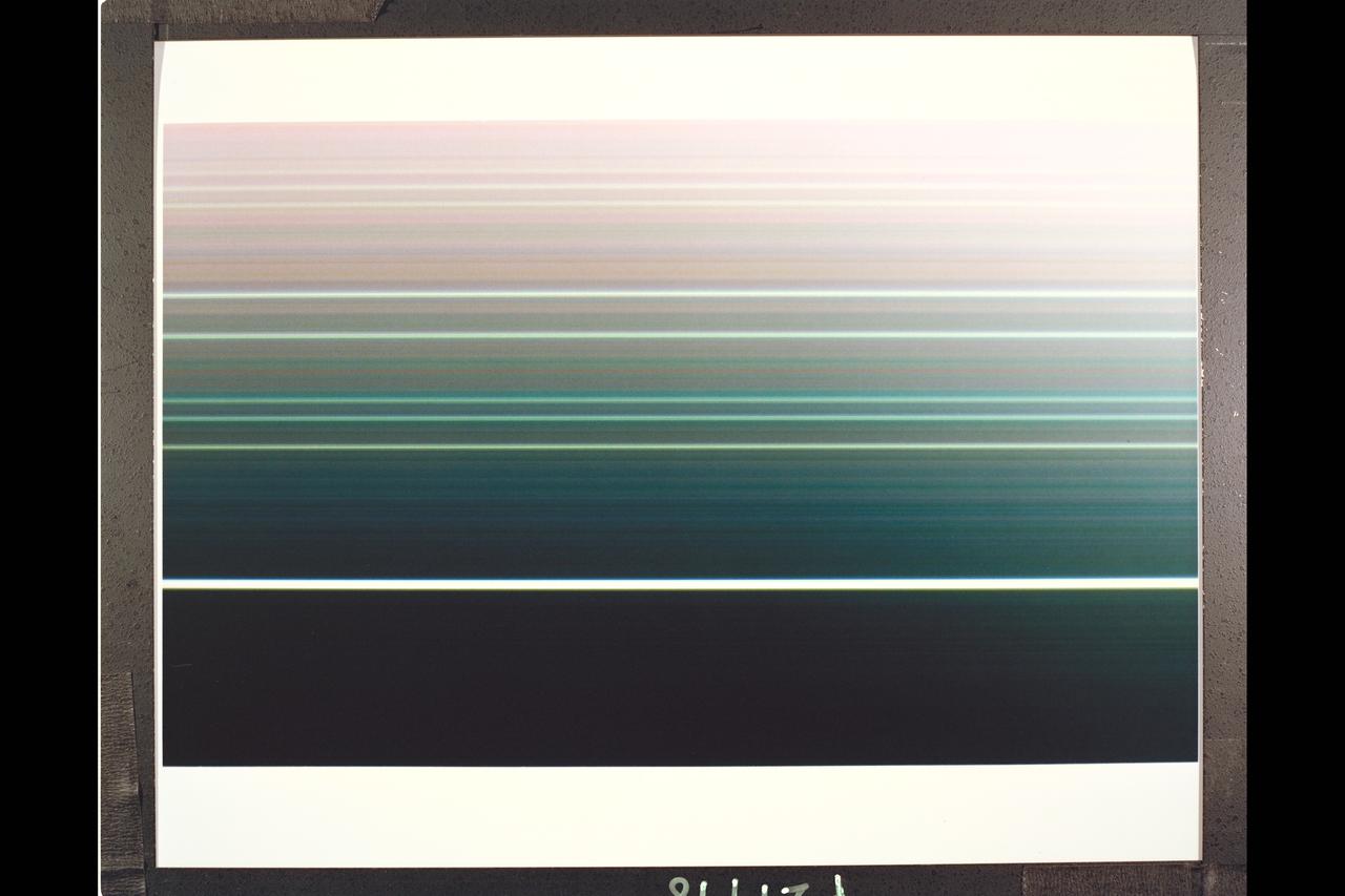 4.17 million miles (2.59 million miles) Resolution :  40 km. (25mi.) P-29498C This false color, Voyager 2 composite view of all nine of Uranian rings  was made from six 15 second exposures through the narrow angle camera. The special computer processing  used to extract color information from the extremely dark and faint rings, causing the even fainter, pastel lines seen between the rings. Two images, each in the green, clear, & violet filters, were added together and averaged to find the proper color difference between the rings. the final image was made from these three color averages and represents an enhanced, false color view. The image shows that the brightest, or Epsilon ring, at top ,is neutral in color, with the fainter eight other rings showing color differences between them. moving down, toward, Uranus, we see the Delta, Gamma, & Eta rings in shades of blue and green; the Beta & Alpha rings in somewhat lighter tones; and then finally, a set of three, known simply as 4, 5, & 6 rings, in faint off-white tones. Scientists will use this color information to try to understand the nature and origin of the ring material.