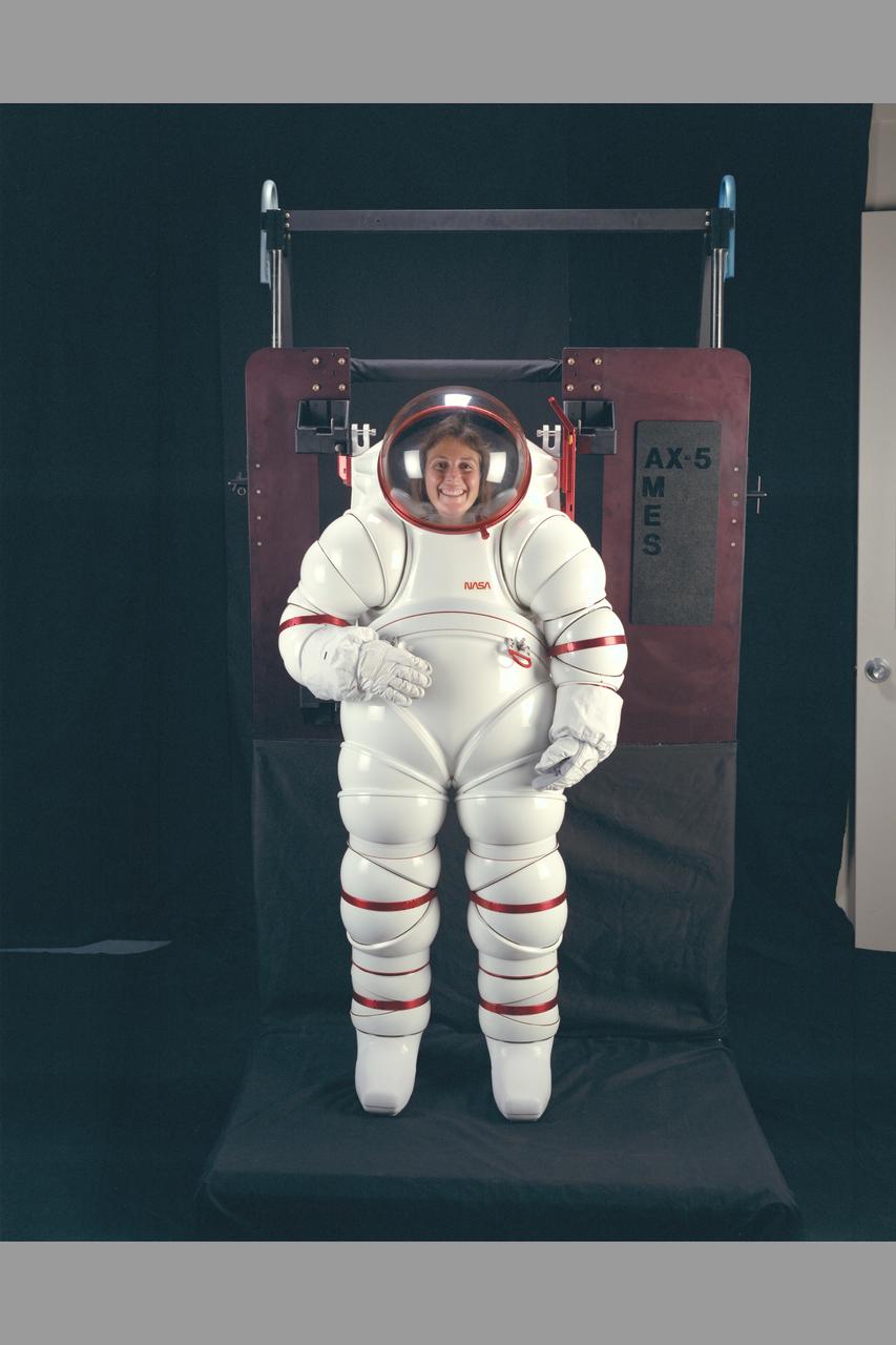 AX-5 Space Suit (Hardsuit) attached to donning stand: This demonstration of new sizing techniques shows the suit adjusted to accommodate the Astronaut's small size.  The hardsuit while maintaining mobility offers the astronaut greater protection from debris, micrometerorite penetration, radiation and thermal loads during EVA operations.  Developed by NASA Ames. Designer/engineer Hubert 'Vic'  Vykukal