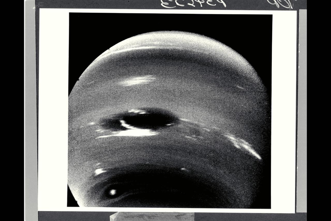 Range : 6.1 million km ( 3.8 million miles) This image of clouds in Neptune's atmosphere is the first that tests the accuracy of the weather forecast that was made eight days earlier to select targets for the Voyager narrow-angle camer. Three of the four targeted features are visible in this photograph; all three are close to their predicted locations. The Great Dark Spot with its bright white companion is slightly to the left of center. The small brig&ht Scooter is below and to the left, and the second dark spot with its bright core is below the Scooter. Strong eastward winds -- up to 400 mph -- cause the second dark spot to overtake and pass the larger one every five days.