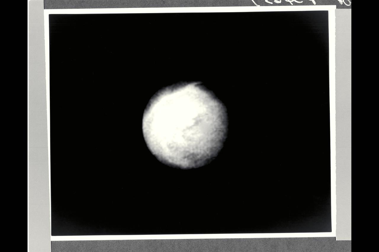 Range : 4 million km (2.5 million miles) Already-intriquing patterns of unknown origin appear on the surgace of Neptune's largest satellite, Trition, in this image from Voyager 2. Voyager images show that Trition's diameter is about 2,720 km (1,690 miles), and that it is one of the brightest objects in the solar system, reflecting about 70 percent of the sunlight that strikes it. THis is the hemisphere of Triton that always faces away from Neptune. The south pole is near the botton of the image. Triton's rotation axis is tilted so that the latitude at the center of the disk is 55 degrees south. Dark regions at the top of the disk extend from roughly the equator to beyond 20 degrees north. The margin between the bright and dark regions varies with longitude around the satellite. The gray, featureless area just to the right of the center of the disk is due to a reseau (reticule mark) in the camera.