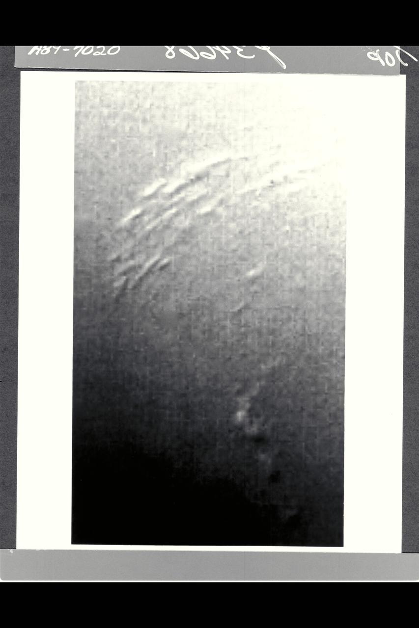 P-34668 Range :  25 million km. ( 16 million miles ) Smallest Resolvable Feature :  45 km or 28 miles This Voyager 2 image of Neptune,  shot with a narrow angle camera,  shows the discovery of shadows in Neptune's atmosphere. The shadows cast onto deep cloud banks by smaller elevated clouds. Located at about 68 degrees south latitude, they are the first cloud shadows ever seen by Voyager on any planet. The dark regions adjacent to the small bright clouds are believed to be shadows, because they are on the side of the cloud that is opposite to the incoming sunlight and because they lengthen in places where the sun lies closer to the horizon. Estimates of the height of these discrete clouds above the  underlying cloud bank can be obtained by careful analysis of this data.