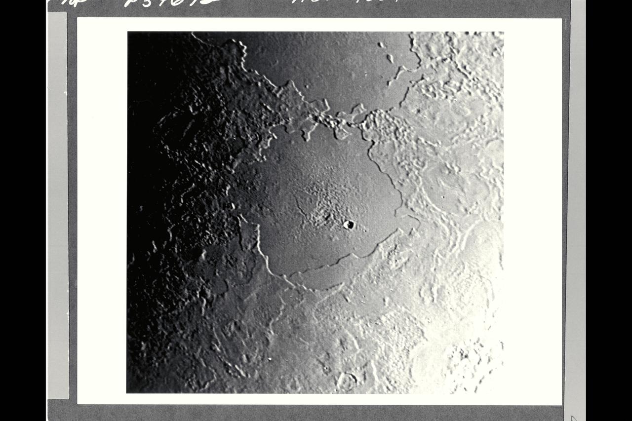 P-34692 Range : 500 km. ( 300 miles ) Smallest Resolvable Feature : 900 m. or 2,700 ft. Part of Triton's complex geological history canbe seen in this image, shot by Voyager 2. Part of a sequence, this photograph encompasses two depressions, possibly old impact basins, that have been extensively modified by floodind, melting, faulting, and collapse. Several episodes of filling and partial removal of material appear to have occurred. The rough area in the middle of the bottom depression probably marks the most recent eruption of material. Only a few impact craters dot the area, which shows the dominance of internally driven geologic processes on Triton.