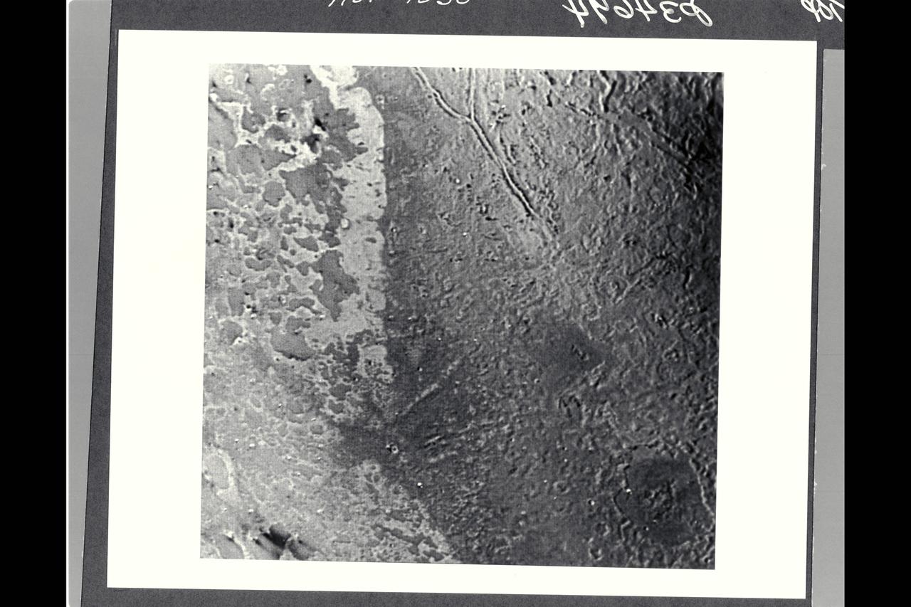P-34692 Range : 500 km. ( 300 miles ) Smallest Resolvable Feature : 900 m. or 2,700 ft. Part of Triton's complex geological history canbe seen in this image, shot by Voyager 2. Part of a sequence, it shows a surface dominated by many roughly circular, polygonal, and arcuate features between 30 and 50 km (18 and 30 miles ) across. Some resemble degraded impact craters of Mars, while others resemble the 'palimpsest' features of Jupiter's satellite Ganymede. Peculiar intersecting, double ridged lines are 15 to 20 km. or 9 to 12 miles wide and hundreds of kilometers long. Theyresemble some deformational belts of Ganymede. Patches of plainsforming material tend to occur in local depressions. The geologic features of Triton and spectroscopic information indicates that the surface of Triton is underlain by a mixture of ices.