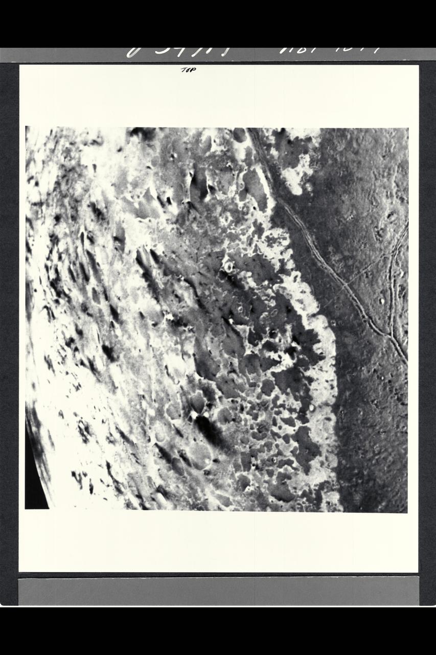 P-34714 This image of the south polar terrain of Triton reveals about 50 dark plumes or 'wind streaks' on the icy surface. The plumes originate at very dark spots generally a few miles in diameter and some are more than 100 miles long. The spots which clearly mark the source of the dark material may be vents where gas has erupted from beneath the surface and carried dark particles into Triton's nitrogen atmosphere. Southwesterly winds then transported the erupted particles, which formed gradually thinning deposits to the northeast of most vents. It is possible that the eruptions have been driven by seasonal heating of very shallow subsurface deposits of volatiles, and the winds transporting particles similiarly may be seasonal winds. The polar terrain, upon which the dark streaks have been deposited, is a region of bright materials mottled with irregular, somewhat dark patches. The pattern of irregular patches suggests that they may correspond to lag deposits of moderately dark material that cap the bright ice over the polar terrain.