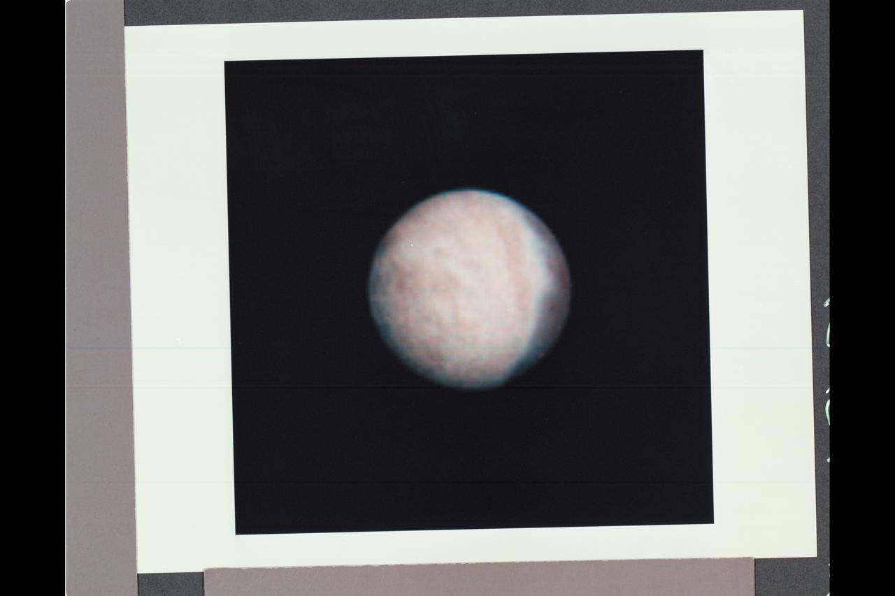 Range : 5.4 million km (3.3 million miles) Features as small as 100 km (62 miles) across can be seen in this color image of Neptune's satellite Triton, photographed by Voyager 2. Triton's overall pinkish color may be due to reddish materials produced by irradiation of methane gas and ice on the satellite. The dark areas near the top of the image seem to be part of a belt of dark markings observed near Trition's equator at different longitudes. Generally, darker areas on Triton appear to be somewhat redder in color than brighter areas. The central longitude in the image is 123 degrees. Here the south pole is at about 6 o'clock, approximately 1/6th of the way up from the bottom. The color image was made from three black-and-white frames, taken through clear, violet and green filters.