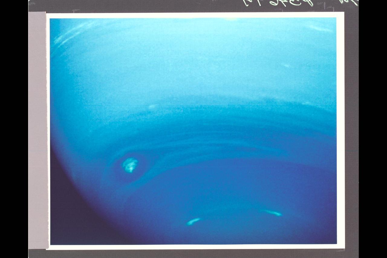 Range :  4.2 million km. ( 2.6 million miles ) P-34649 This photograph of Neptune's southern hemisphere taken by Voyager 2's narrow angle camera, through the green and clear filters.  The smallest feature that can be seen are 38 km ( 24 miles ) across. the almond shaped structure at the left is a  large cloud system that has been seen for several weeks. Internal details in the feature have become increasingly apparent as Voyager 2 has approached. Systems with similiar shapes in Jupiter's atmosphere rotate about their centers, rolling in the local winds that increase toward the south. However, the wispy nature of the white central clouds in this Neptunian feature make confirmation of the syste.m's rotation difficult