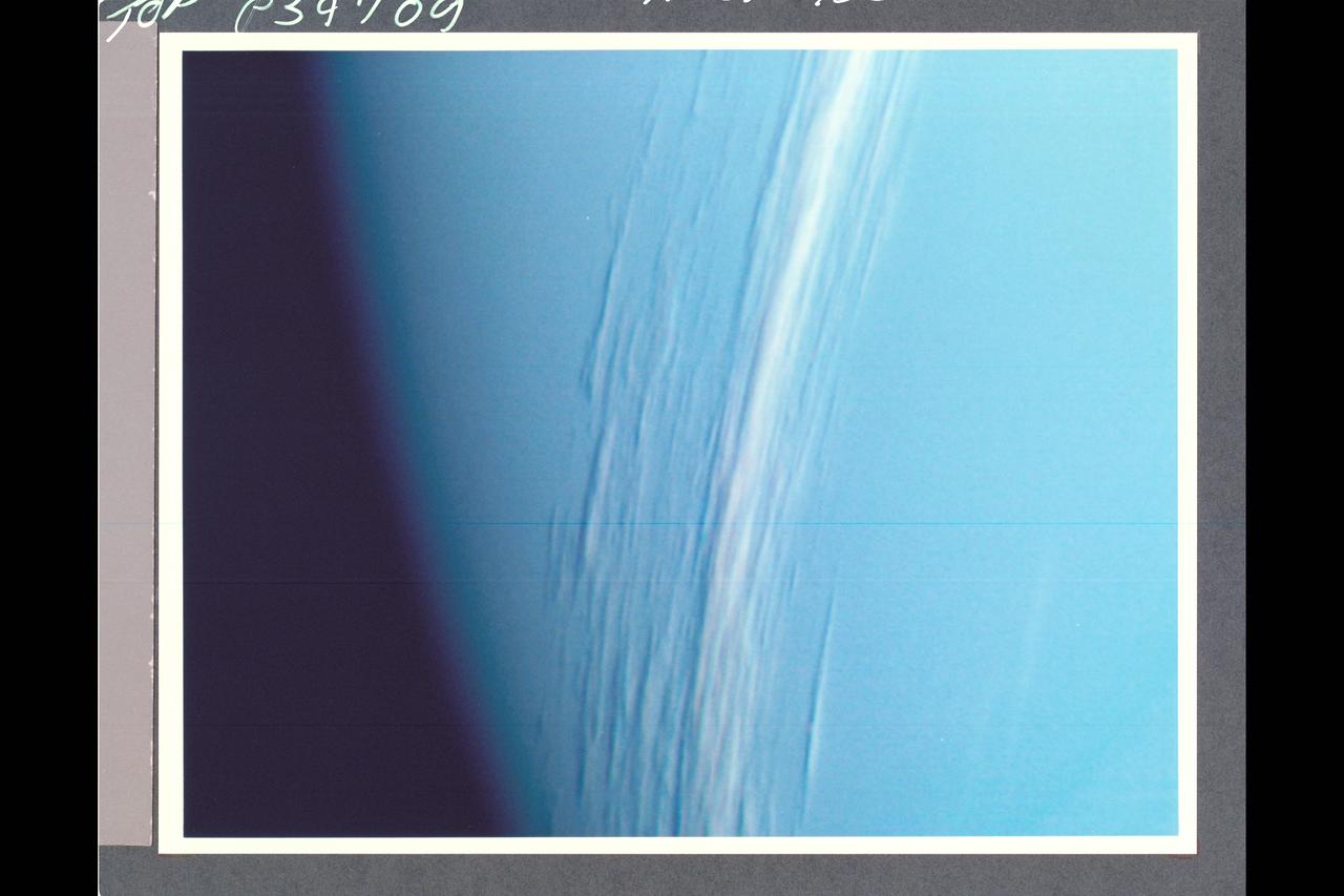 P-34709 Range: 157,000 kilometers (98,000 miles) This Voyager 2 high resolution color image, taken 2 hours before closest approach, provides obvious evidence of vertical relief in Neptune's bright cloud streaks. These clouds were observed at a latitude of 29Â° N near Neptune's east terminator. The linear cloud forms are stretched approximately along lines of constant latitude and the sun is toward the lower left. The bright sides of the clouds that face the sun are brighter than the surrounding cloud deck because they are more directly exposed to the sun. Shadows can be seen on the side directly opposite the sun. These shadows are less distinct at short wavelengths (violet filter) and more distinct at long wavelengths (orange filter). This can be understood if the underlying cloud deck on which the shadow is cast is at a relatively great depth, in which case scattering by molecules in the overlying atmopsphere will diffuse light into the shadow. Because molecules scatter blue light much more efficiently than red light, the shadows will be darkest at the longest (reddest) wavelengths, and will appear blue under white illumination. The resolution of this image is 11 kilometers (6.8 miles per pixel). The width of the cloud streaks range from 50 to 200 kilometers (31 to 124 miles), and their shadow widths range from 30 to 50 kilometers (18 to 31 miles). Cloud heights appear to be of the order of 50 kilometers (31 miles). This corresponds to 2 scale heights.