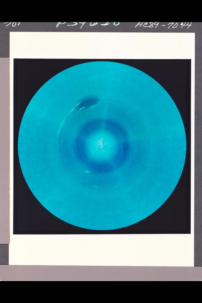 Range : 30 million km. ( 18.6 million miles ) P-34628 C The south pole of Neptune is at the center of this polar projection made from five color images taken by Voyager 2 over the course of one Neptunian day-- about 18 hours. Latitude lines are concentric circles, and the outer circle is at about 15 degrees north latitude. Cloud paterns are organized by the planet's rotation and are generally concentric with the pole . Oval storms, which drift in longitude at relative speeds up to 400 miles an hour, disrupt the circular symmetry. The color composite was made from black and white frames through the Voyager narrow angle camera's clear, orange, and green filters.