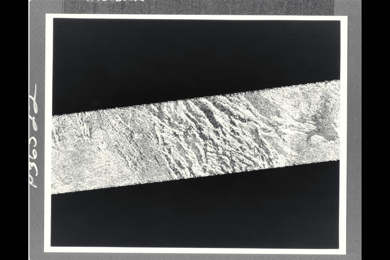 This portion of a Magellan radar image strip shows a small region on Venus 20 km (12.4 mi.) wide and 75 km (50 mi.) long on the east flank of a major volcanic upland called Beta Regio. The image is centerd at 23 degrees north latitude and 286.7 degrees east longitude. The ridge and valley networkin the middle part of the image is formed by intersection faults which have broken the Venusian crust into a clomplex, deformed type of surface called tessera, the Latin word for tile. The parallel mountains and valleys resemble the Basin and Range Province in the western United States. The irregular dark patch near the top of the image is a smooth surface, probably formed by lava flows in a region about 10 km (6 mi.) across. Similar dark surfaces within the valleys indicate lava flows that are younger than the tessera giving an indication of the geologic time relationships of the events that formed the present surface. The image has a resolution of 120 meters (400 feet).
