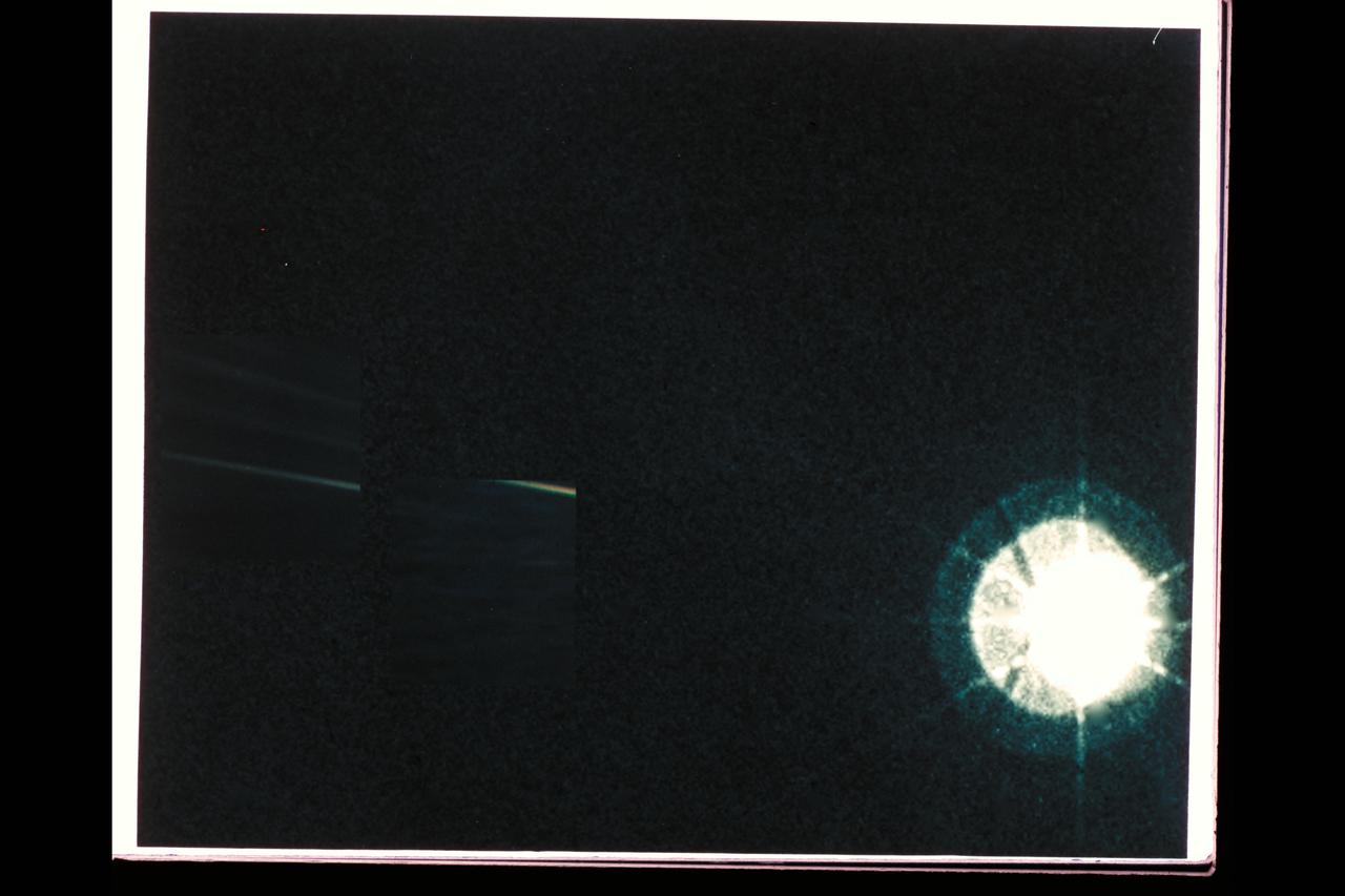 Range : 4 billion miles from Earth, at 32 degrees to the ecliptic. P-36057C This color image of the Sun, Earth, and Venus is one of the first, and maybe, only images that show are solar system from such a vantage point. The image is a portion of a wide angle image containing the sun and the region of space where the Earth and Venus were at the time, with narrow angle cameras centered on each planet. The wide angle was taken with the cameras darkest filter, a methane absorption band, and the shortest possible exposure, one two-hundredth of a second, to avoid saturating the camera's vidicon tube with scattered sunlight. The sun is not large in the sky, as seen from Voyager's perpective at the edge of the solar system. Yet, it is still 8xs brighter than the brightest star in Earth's sky, Sirius. The image of the sun you see is far larger than the actual dimension of the solar disk. The result of the brightness is a bright burned out image with multiple reflections from the optics of the camera. The rays around th sun are a diffraction pattern of the calibration lamp which is mounted in front of the wide angle lens. the 2 narrow angle frames containing the images of the Earth and Venus have been digitally mosaicked into the wide angle image at the appropriate scale. These images were taken through three color filters and recombined to produce the color image. The violet, green, and blue filters used , as well as exposure times of .72,.48, and .72 for Earth, and .36, .24, and .36 for Venus.The images also show long linear streaks resulting from scatering of sulight off parts of the camera and its shade.