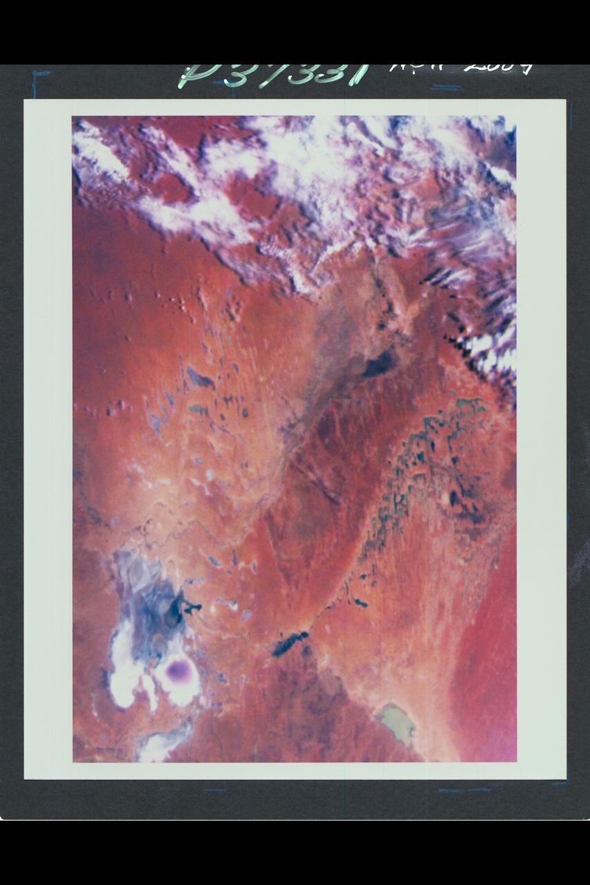 Range :  35,000 miles plus. This color image of the Simpson Desert in Australia was obtained by the Galileo spacecraft at aboaut 2:30 pm PST.  The color composite was made from images taken through the red, green and violet filters.  The area shown, about 280 miles wide by about 340 miles north-to-south, is southeast of Alice Springs.  At lower left is Lake Eyre, a salt lake below sea level, subject to seasonal water-level fluctuations; when this image was acquired the lake was nearly dry.  At lower right is the greenish Lake Blanche.  Fields of linear sand dunes stretch north and east of Lake Eyre, shaped by prevailing winds from the south and showing, in different colors, the various sources and/or ages of their sands.
