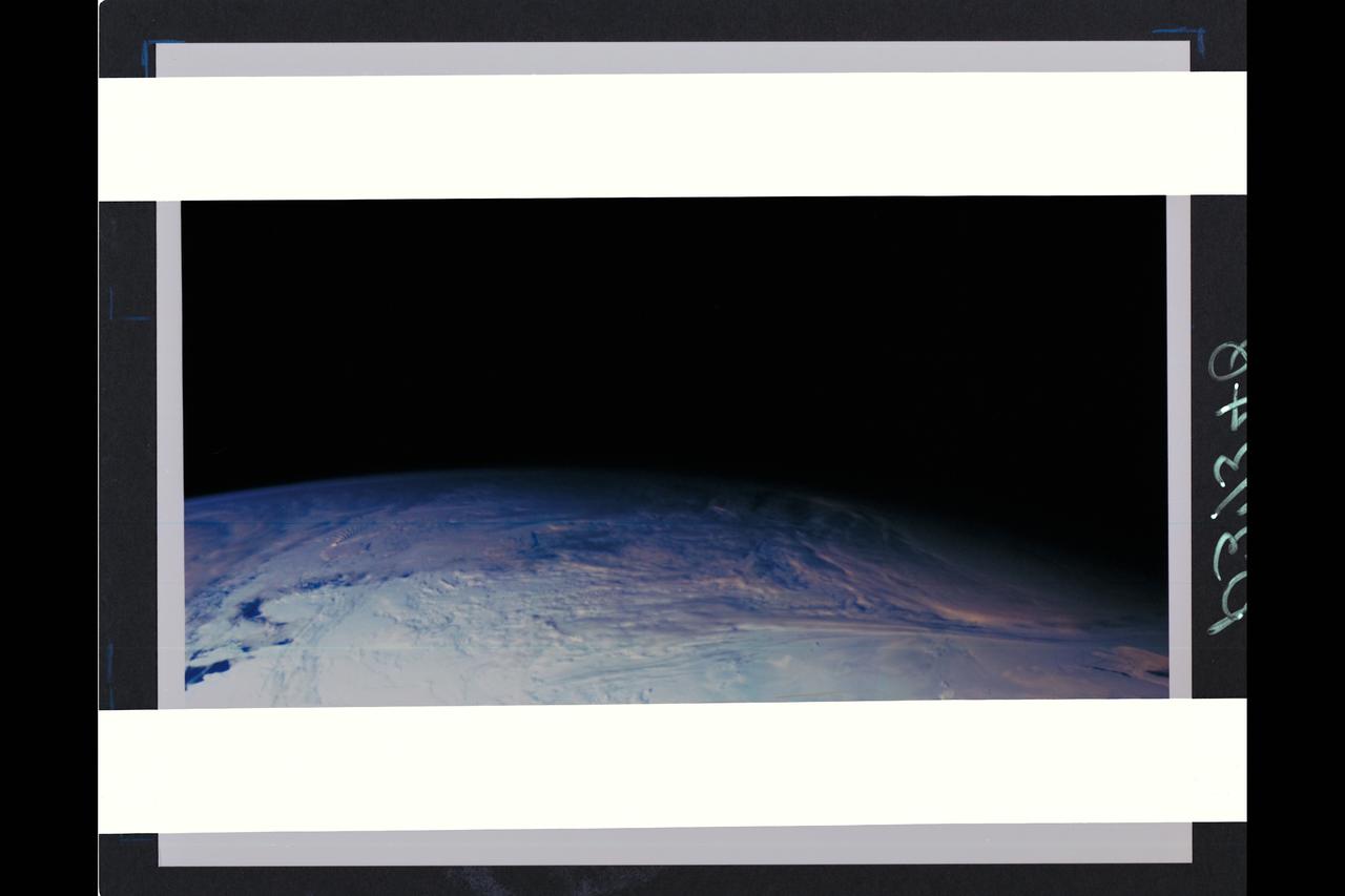 This color picture of the limb of the Earth, looking north past Antarctica, is a mosaic of 11 images taken during a ten-minute period near 5:45 p.m. PST Dec. 8, 1990, by Galileo's imaging system.  Red, green and violet filters were used.  The picture spans about 1,600 miles across the south polar latitudes of our planet  The morning day/night terminator is toward the right.  The South Pole is out of sight below the picture;  the visible areas of Antarctica are those lying generally south of South America.  The violet-blue envelope of Earth's atmosphere is prominent along the limb to the left.  At lower left, the dark blue Amundsen Sea lies to the left of the Walgreen and Bakutis Coasts.  Beyond it,  Peter Island reacts with the winds to produce a striking pattern of atmosperic waves. (JPL ref. No. P-37340)