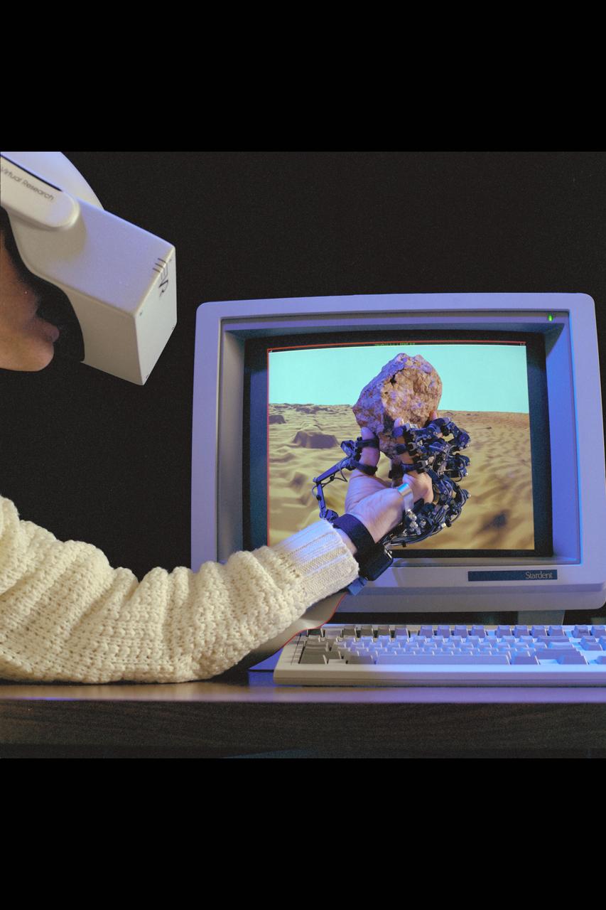 Virtual Environment Telepresence workstation, simulated Mars Exploration shows Dr Michael McGreevy with virtual helmet and EXOS Dexterous interface (holding rock invirtual hand)