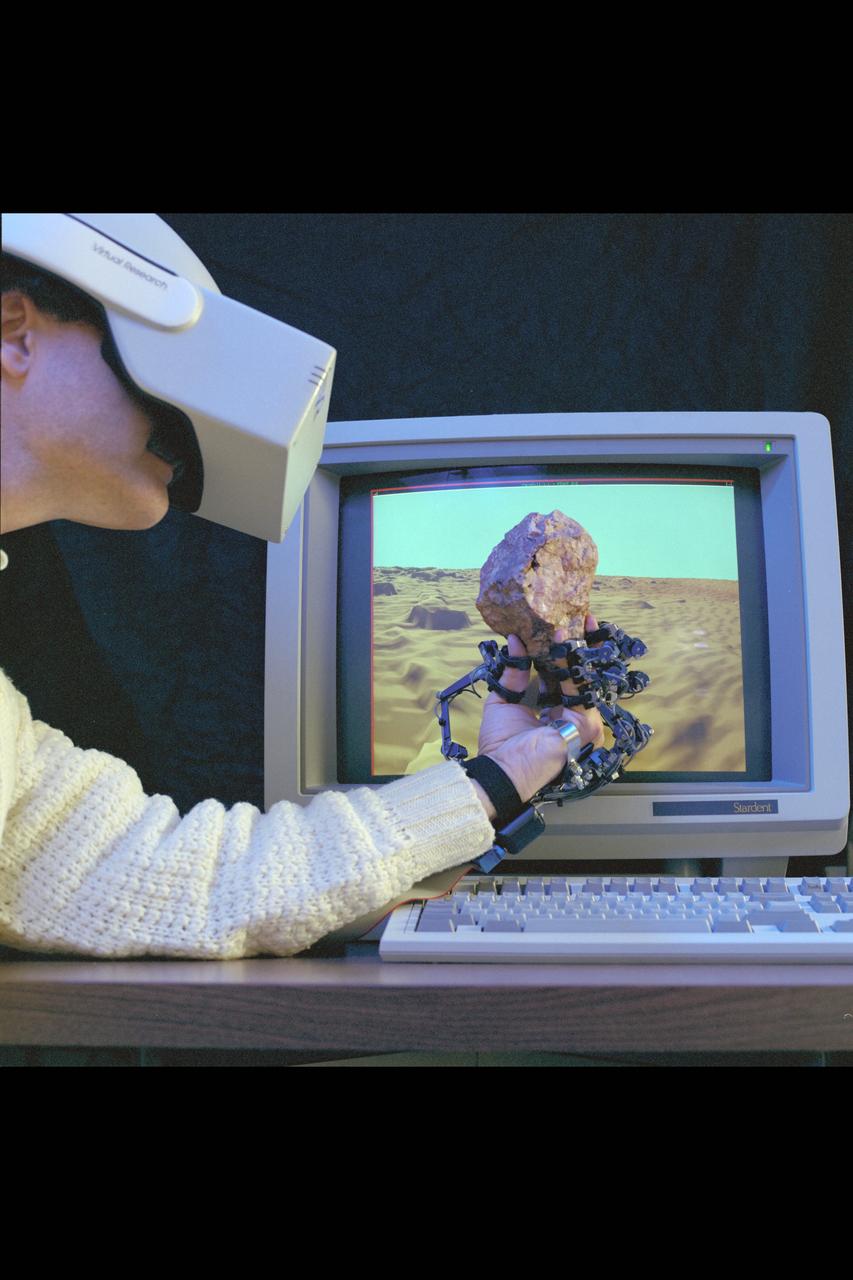 Virtual Environment Telepresence workstation, simulated Mars Exploration shows Dr Michael McGreevy with virtual helmet and EXOS Dexterous interface (holding rock in virtual hand)