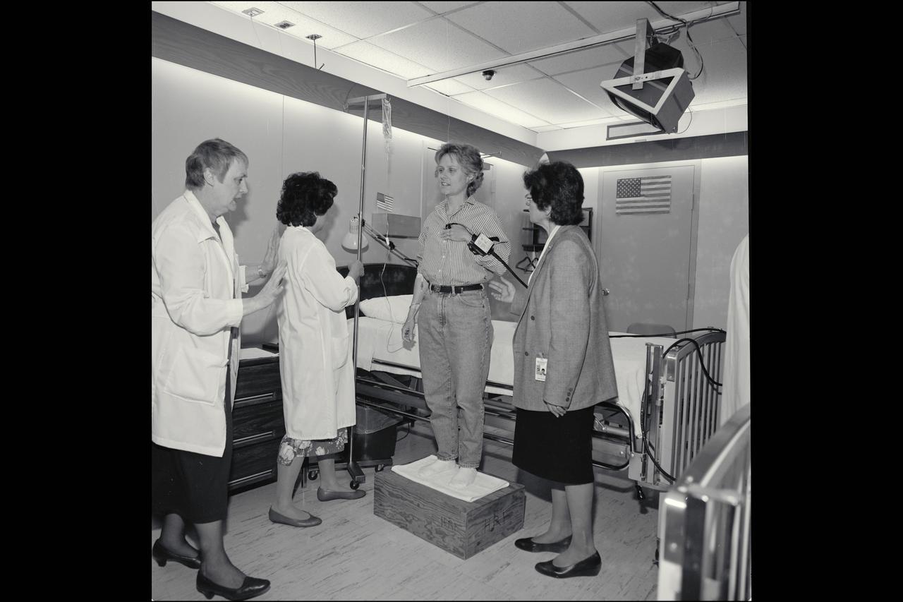 Ann Hutchinson (as subject), Dr. Joan Vernikos (R), Dee O'Hara (L), J. Evans and E. Lowe pose for pictures in the NASA Magazine aritcle 'How it Feels to be a Human Test Subject' as they prepare for a bed rest study to simulate the efects of microgravity on the human body.
