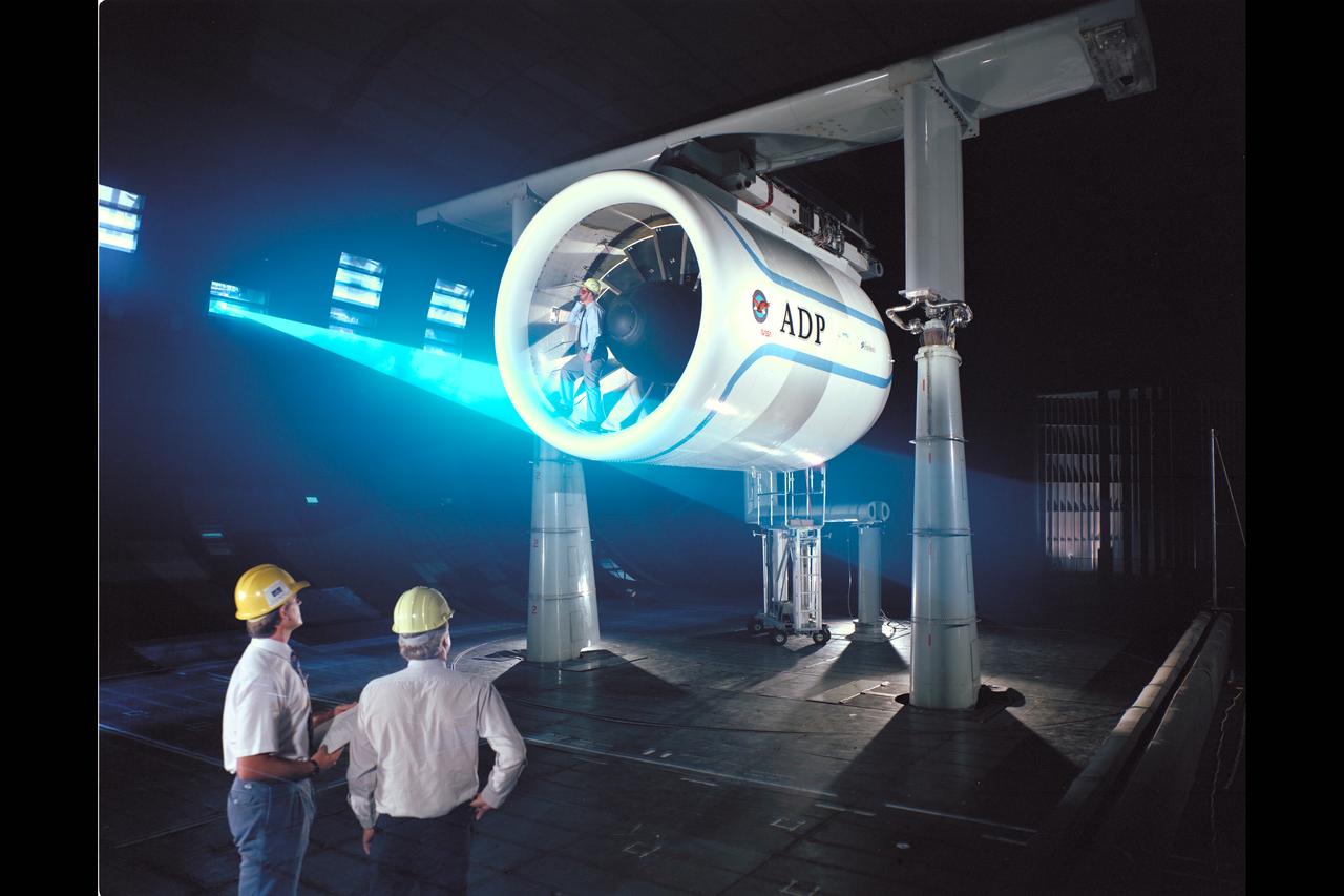 Pratt & Whitney Advanced Ducted Propulsor (ADP) Engine Test-590 in NASA Ames 40x80ft Subsonic Wind Tunnel. The Pratt & Whitney advanced ducted prop (ADP) demonstrator undergoing acoustic and fan performance testing. ADP technology could lead to decreased fuel consumption and noise. Shown here are NASA Ames engineers Peter Zell (left) and Dr Clifton Horne (right) preparing for a laser light sheet for a flow visualization test. Shown standing in the nacelle of the ADP is John Girvin, senior test engineer for Pratt & Whitney.