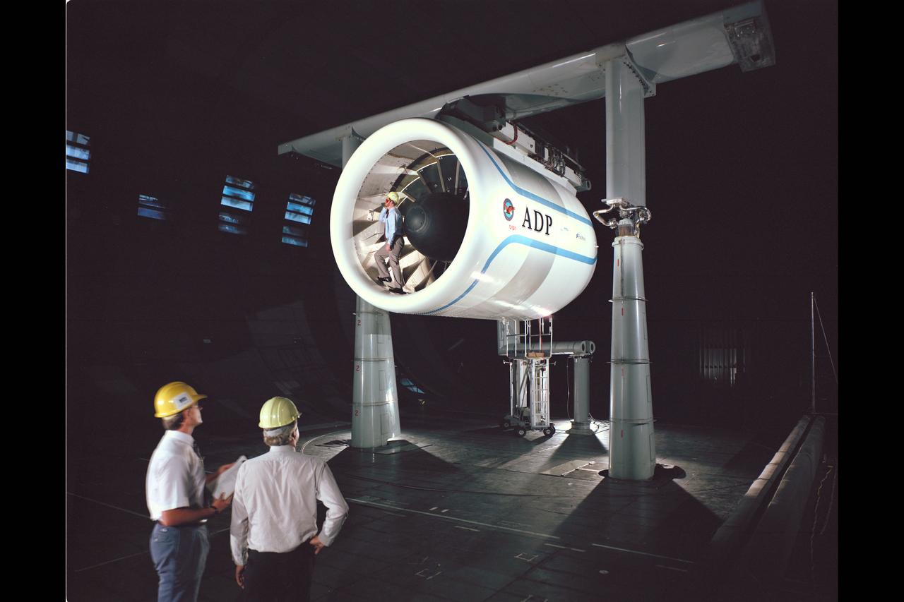 Pratt & Whitney Advanced Ducted Propulsor (ADP) Engine Test-590 in NASA Ames 40x80ft Subsonic Wind Tunnel. The Pratt & Whitney advanced ducted prop (ADP) demonstrator undergoing acoustic and fan performance testing. ADP technology could lead to decreased fuel consumption and noise. Shown here are NASA Ames engineers Peter Zell (left) and Dr Clifton Horne (right) preparing for a laser light sheet for a flow visualization test. Shown standing in the nacelle of the ADP is John Girvin, senior test engineer for Pratt & Whitney.