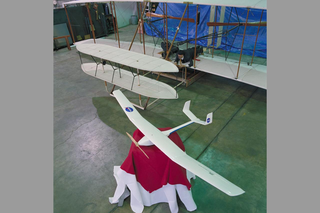A model of the Ames Mars micromission concept aircraft is shown beside the Wright Flyer replica in the high bay of Ames 40x80ft. wind tunnel