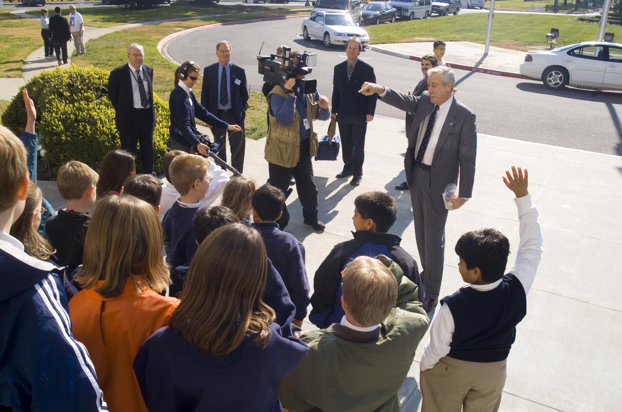 NASA Administrator Sean O'Keefe comes to Ames for employee briefing and tour.  Here he welcomes JASON kids to NASA while handing out patches and pins. Tom Clausen and Donald James, Ames Education  Office in background.