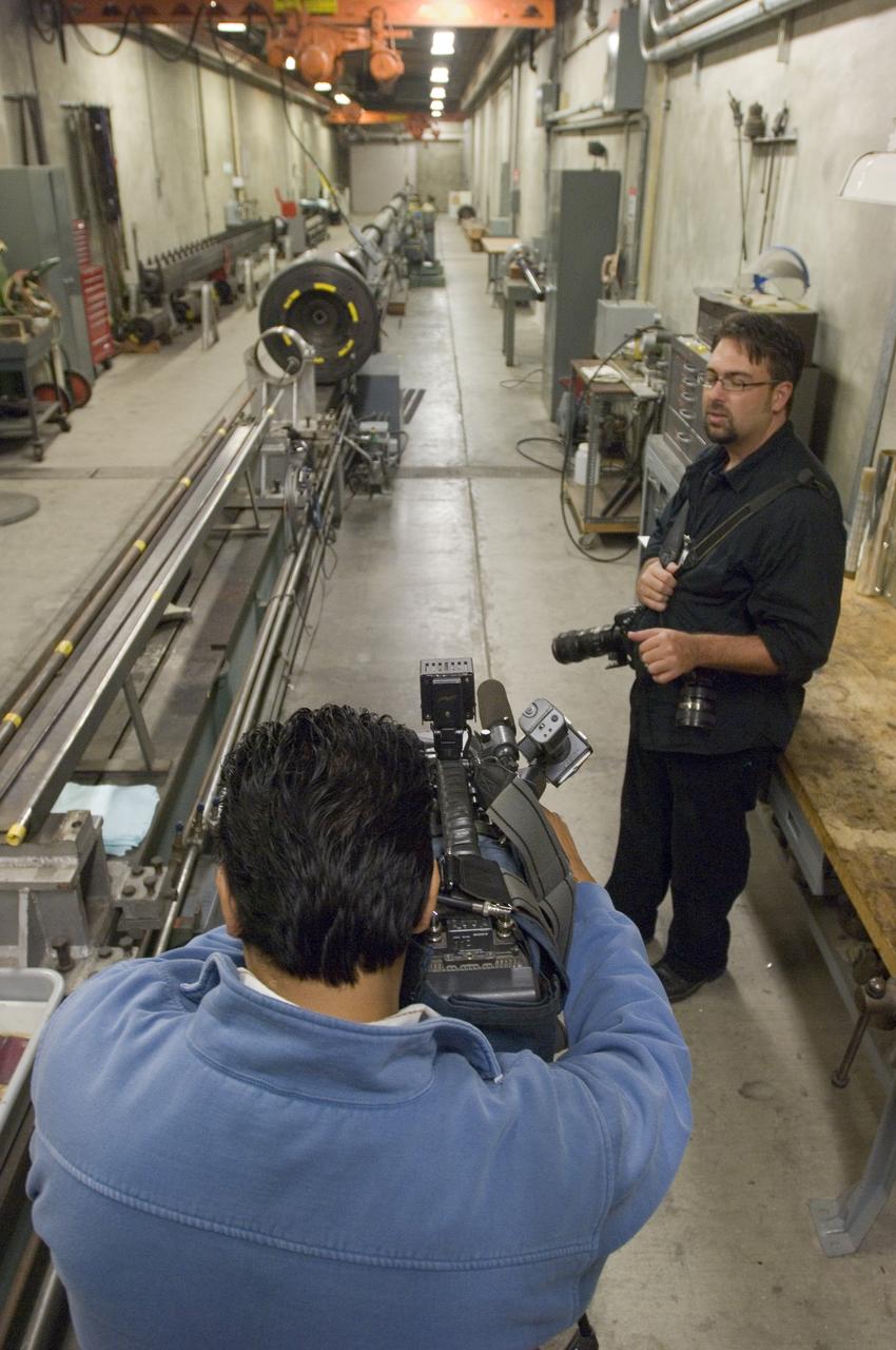 Ames holds a Media Day at the Hypervelocity Free Flight facility where Ames is conducting high-speed tests of small models of the agency's new Orion CEV  to learn about stability during flight. The hypervelocity test facility uses a gun to shoot Orion models between 0.5 and l.5 inches (1.25 - 3.75 centimeters in diameter. The facility can conduct experiments with speeds up to 19,000 miles per hour (30,400 kilometers per hour) - Cesar Acosta, NASA photographer in forground and a news camera men taking shot of the gun facility