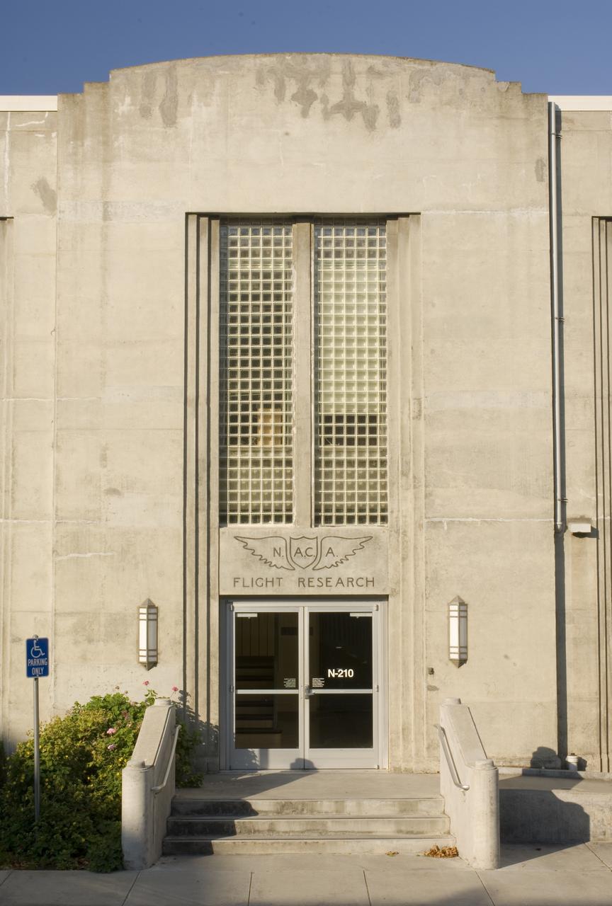 Ames and Moffett Field (MFA) historical sites and memorials Entry of building N-210 Ames Flight System Research Laboratory architectural detail. Eastside showing NACA brass inset wing over front doors, light fixtures flanking the doors and glass brick window wall above the doors