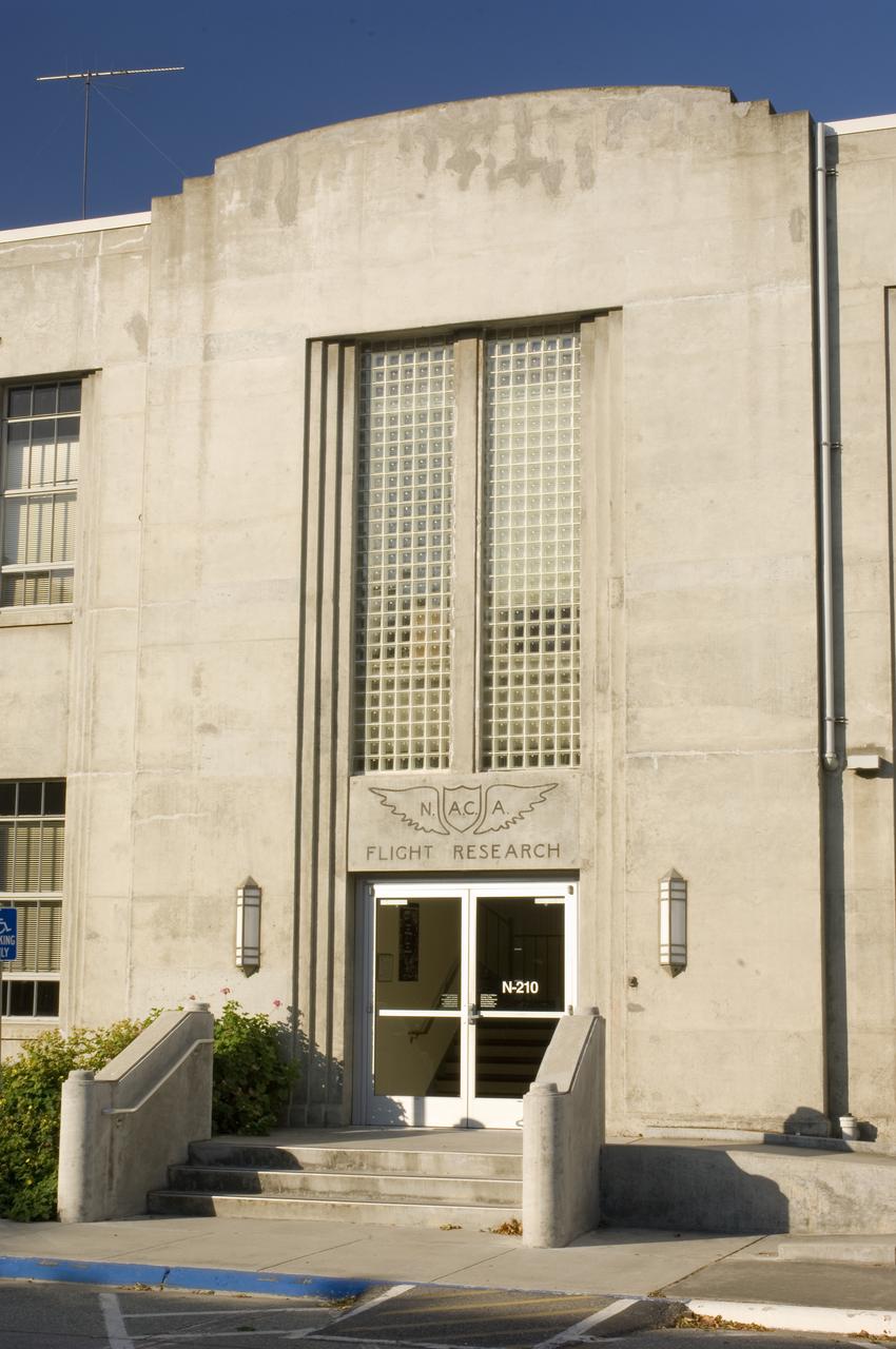 Ames and Moffett Field (MFA) historical sites and memorials Entry of building N-210 Ames Flight System Research Laboratory architectural detail. Eastside showing NACA brass inset wing over front doors, light fixtures flanking the doors and glass brick window wall above the doors