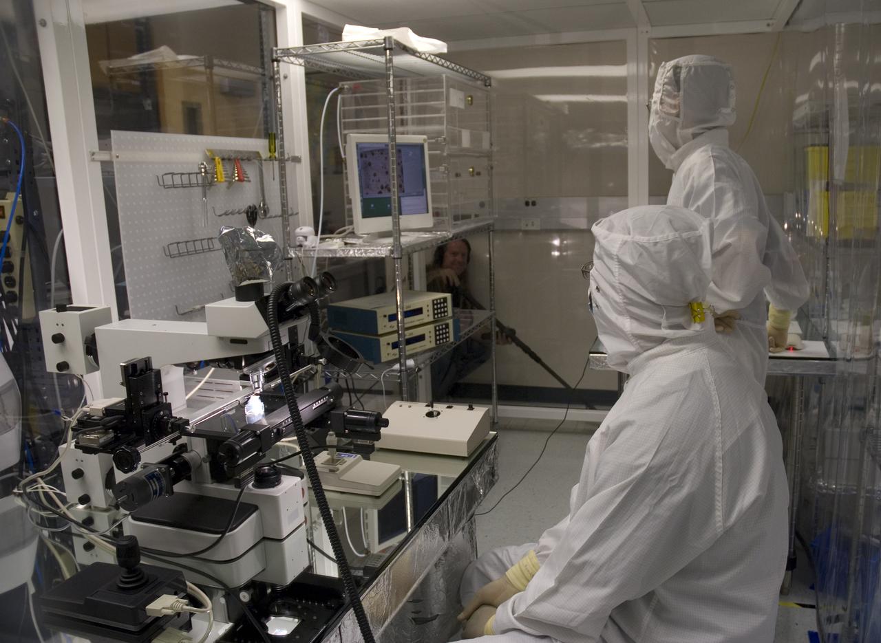 Stardust sample analysis @ UC Berkeley clean room  with Dr Scott Sandford, NASA Ames Astrophysicist - mission samples provided to UC Berkeley for analysis by NASA Berkeley researchers Zack Gainsforth (seated) and Chris Snead working with sample encased in aerogel  Note: Eric Land of NASA/AMES video crew in lower left corner providing sound support for event