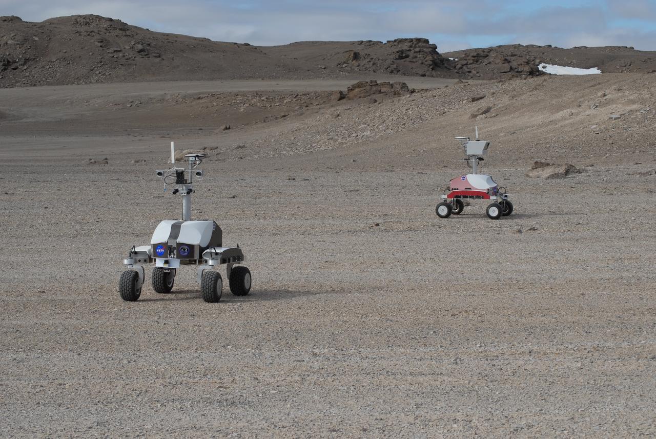 Haughton-Mars Project: - Photo credit to Matt Deans (NASA)  K-10 Rover 'Black' and K-10 'RED' conducting systematic site survey at Haughton Creater Devon Island, Nunavut, in the Canadian high arctic. Which lies in the 'frost rubble zone' of the Earth, i.e., in a polar desert environment and is the only crater known to lie in such an environment. Beginning in 1997, the crater and its surroundings are studied as a promising Mars analog by the NASA-led Haughton-Mars Project.  (photo reference MCD_0888.JPG)