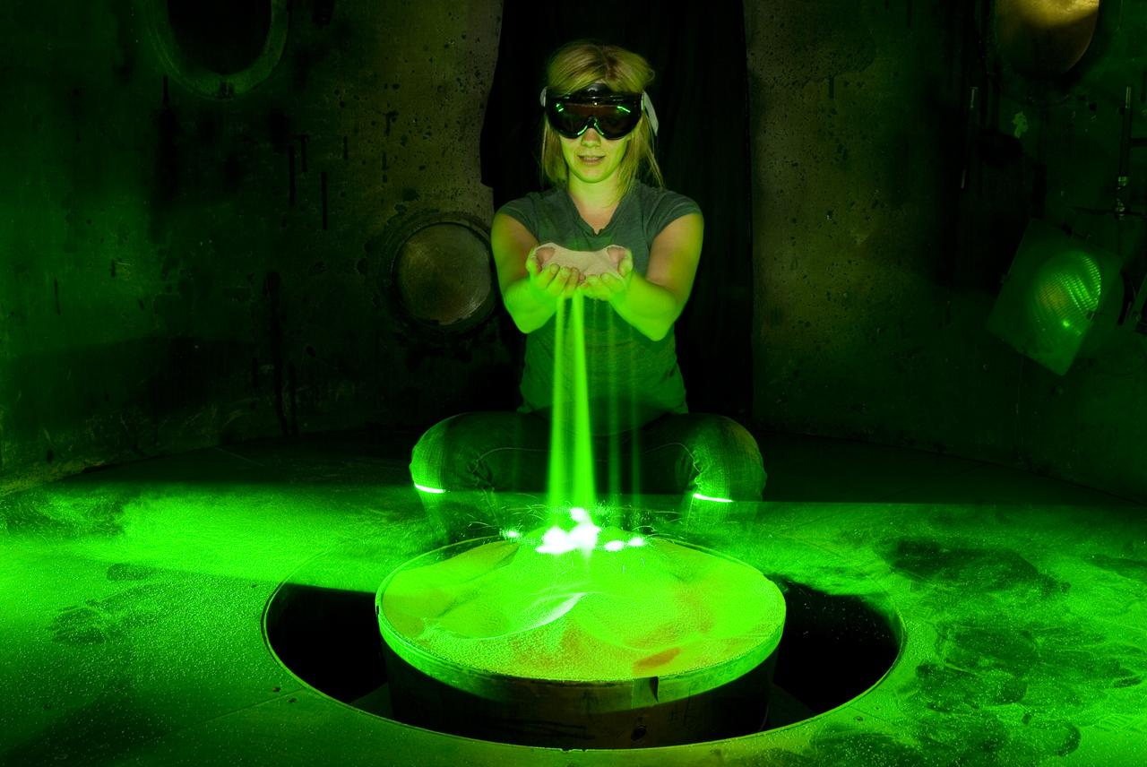 Laura Kushner in test chamber preparing for testing PCI sysem by dropping sand to check laser sheet to be used in study at AVGR (Ames Vertical Gun Range)