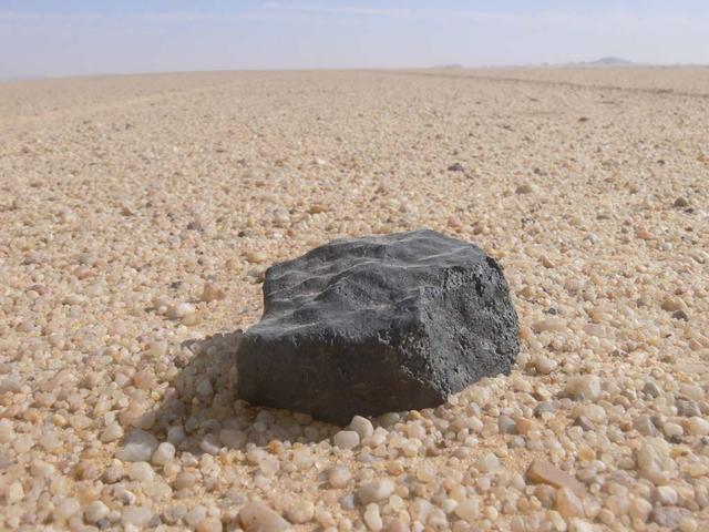 An SUV-sized Asteroid 2008TC# Impacts on October 7, 2008 in the Nubian Desert, Northern Sudan: Dr. Peter Jenniskens, NASA/SETI joined Muawia Shaddas of the University of Khartoum in leading an expedition on a search for samples. Peter Jenniskens finds the brick. Photo Credit: NASA/SETI/P. Jenniskens