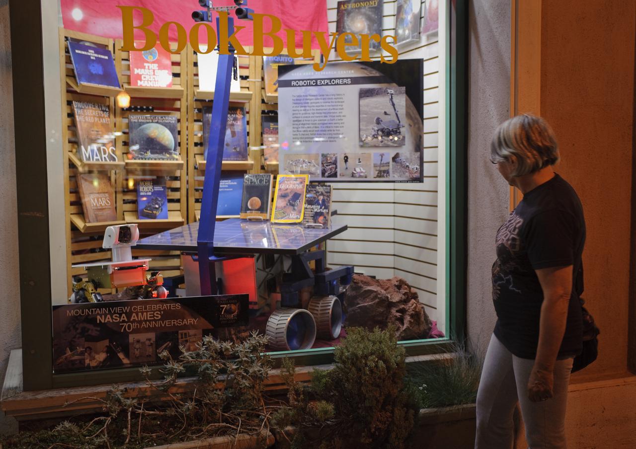 Ames 70 Year Anniversary Exhibit in downtown Mountain View, California. Exhibit in window at Book Buyers. Pedestrian Robin Croft stops to look.