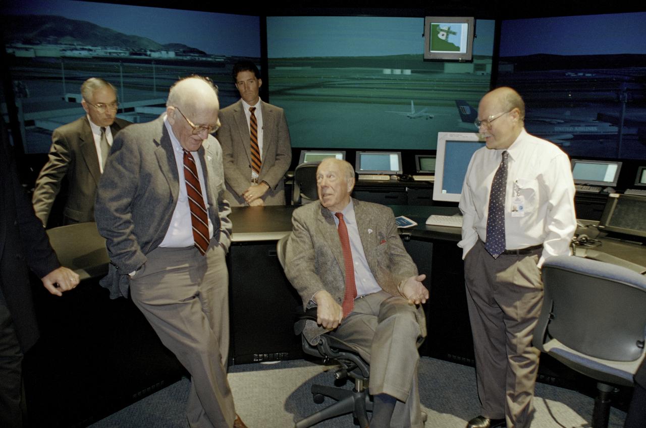 The Honorable George P. Schultz during a Visit and tour of Ames Research Center. Shown here from left to right are in the background Bill Berry, Ames Deputy Director, Dr. Tom Edwards, Chief, Aviation Systems Division, Front row, Dr. Sidney Drell, Staford University, former U S Secretary of State George Schultz,  Dr Richard Haines, Senior Research Csientist, FFC at the Future Flight Central Simulator facility.