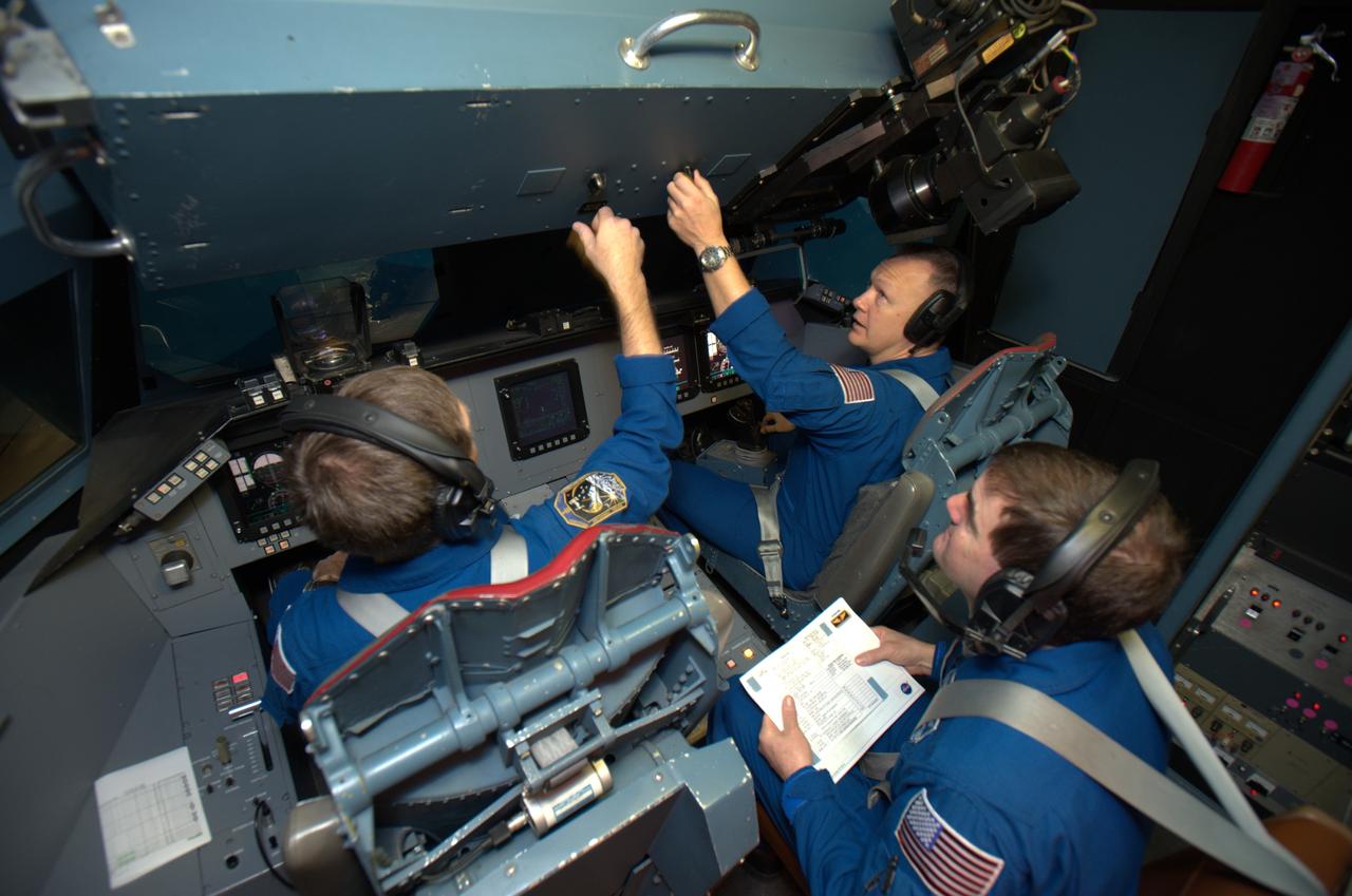 STS-135 astronaut training in the Vertical Motion Simulator, Ames Research Center, Moffett Field, CA. In this overhead view are Chris Ferguson commander on right, Doug Hurley, pilot on left and Rex Walheim, mission specialist, center back  are in VMS S-cab cockpit for simulated landing practice under a variety of landing sites and conditions.