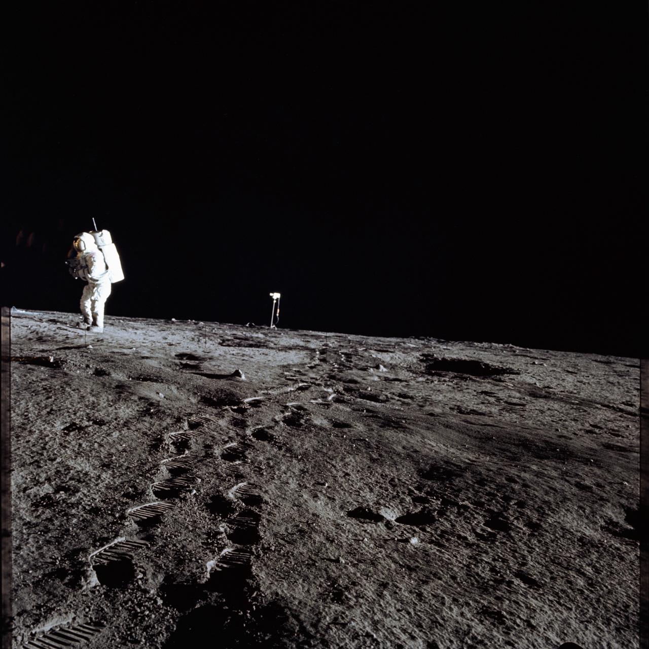 AS12-46-6780 (19 Nov. 1969) --- Astronaut Alan L. Bean, lunar module pilot for the Apollo 12 lunar landing mission, walks from the color lunar surface television camera (center) toward the Apollo 12 Lunar Module (LM - out of frame). The photograph was taken by astronaut Charles Conrad Jr., commander, during the first extravehicular activity (EVA) of the mission. While astronauts Conrad and Bean descended in the LM "Intrepid" to explore the Ocean of Storms region of the moon, astronaut Richard F. Gordon Jr., command module pilot, remained with the Command and Service Modules (CSM) "Yankee Clipper" in lunar orbit.